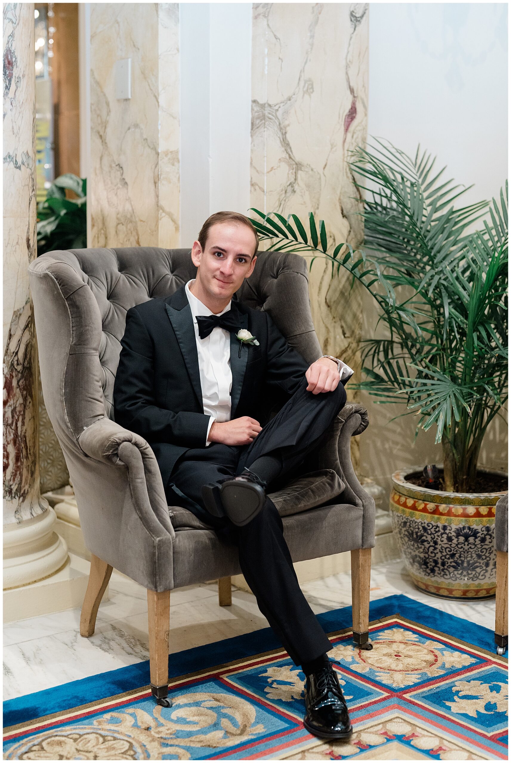 groom sits in chair at Fairmont Copley Plaza hotel in Boston