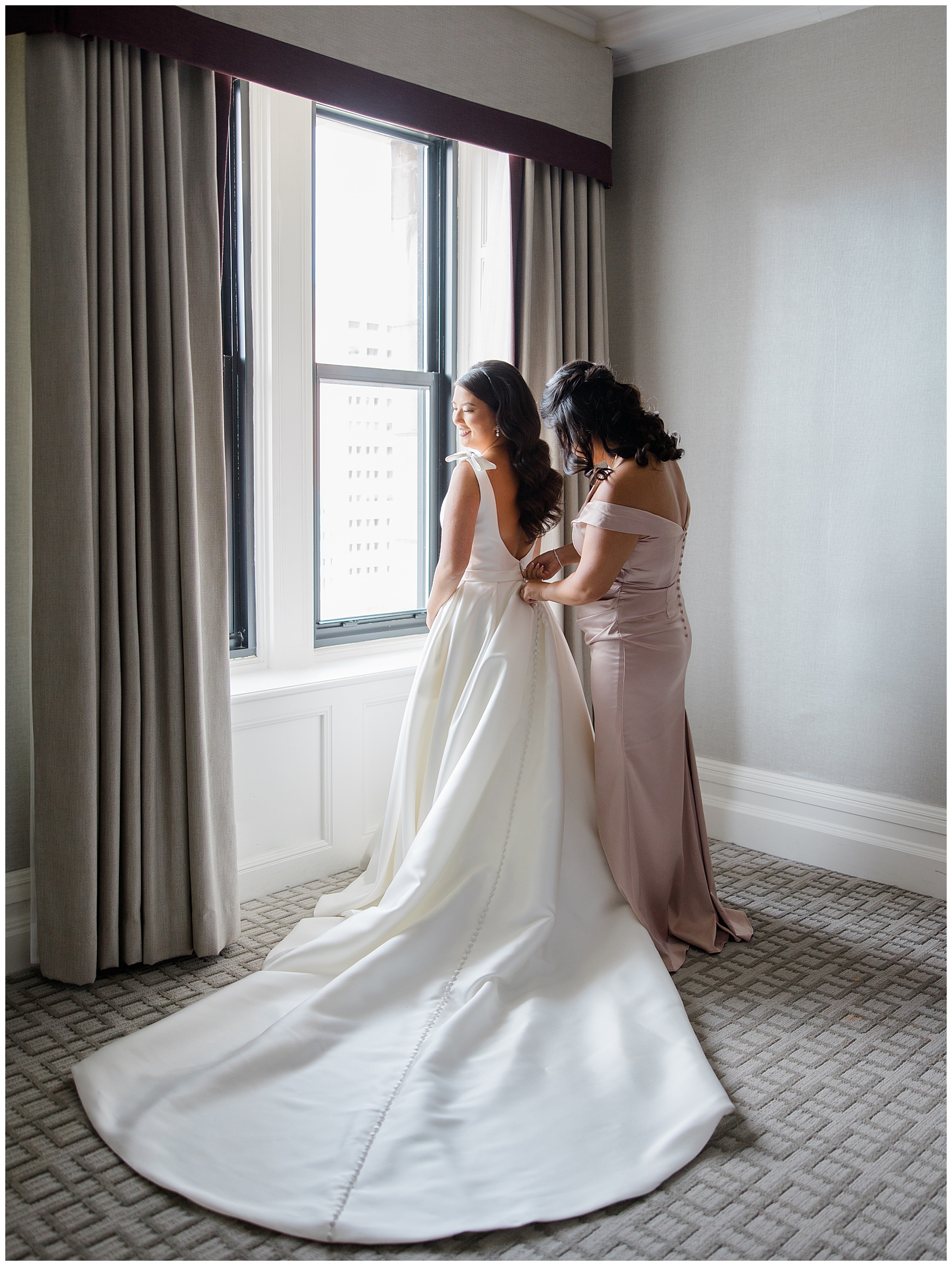 Bride getting into wedding dress with bridesmaid