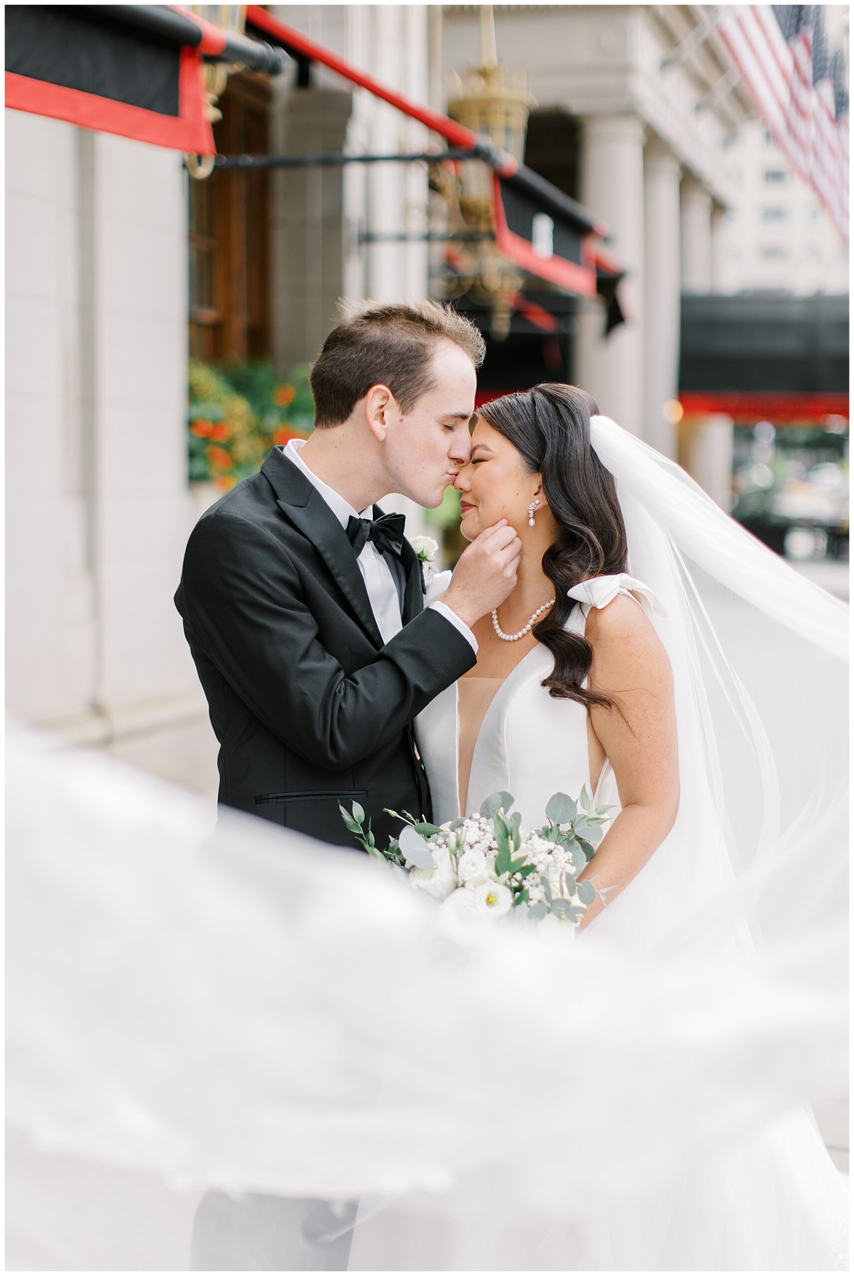 groom kisses bride as her veil flows around them