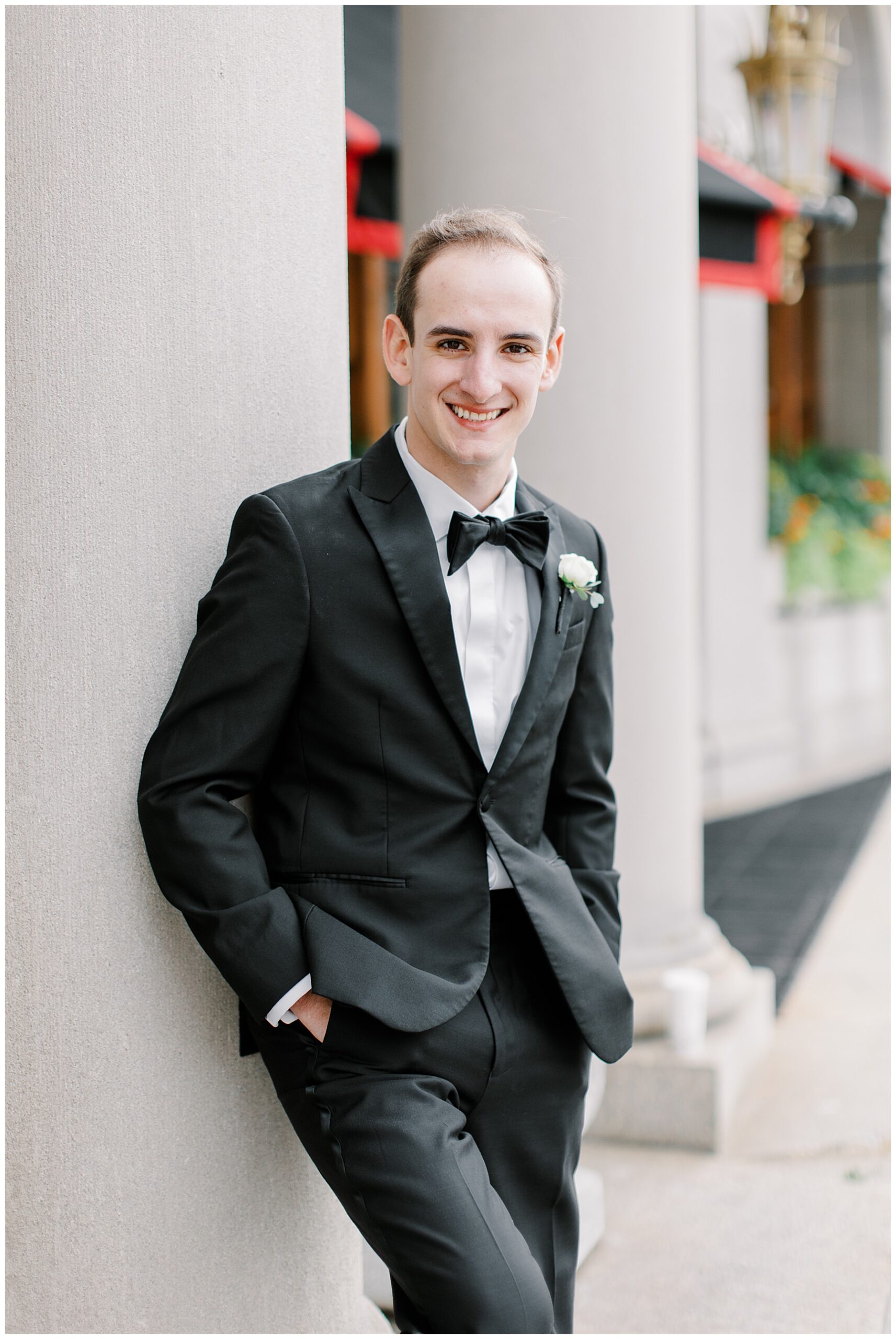 groom leans against pillar for portraits