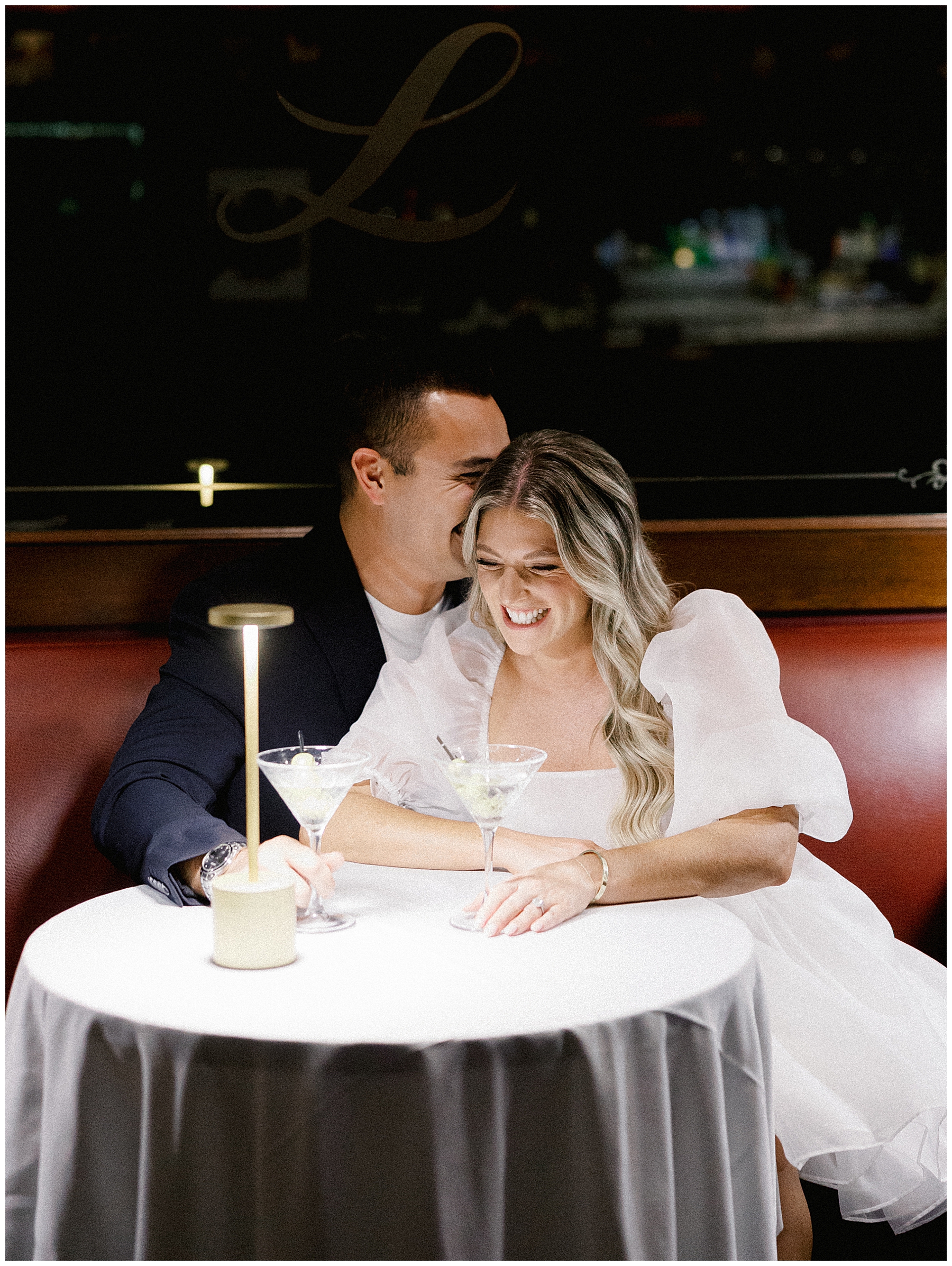 candid engagement photo if couple sitting in booth at restaurant