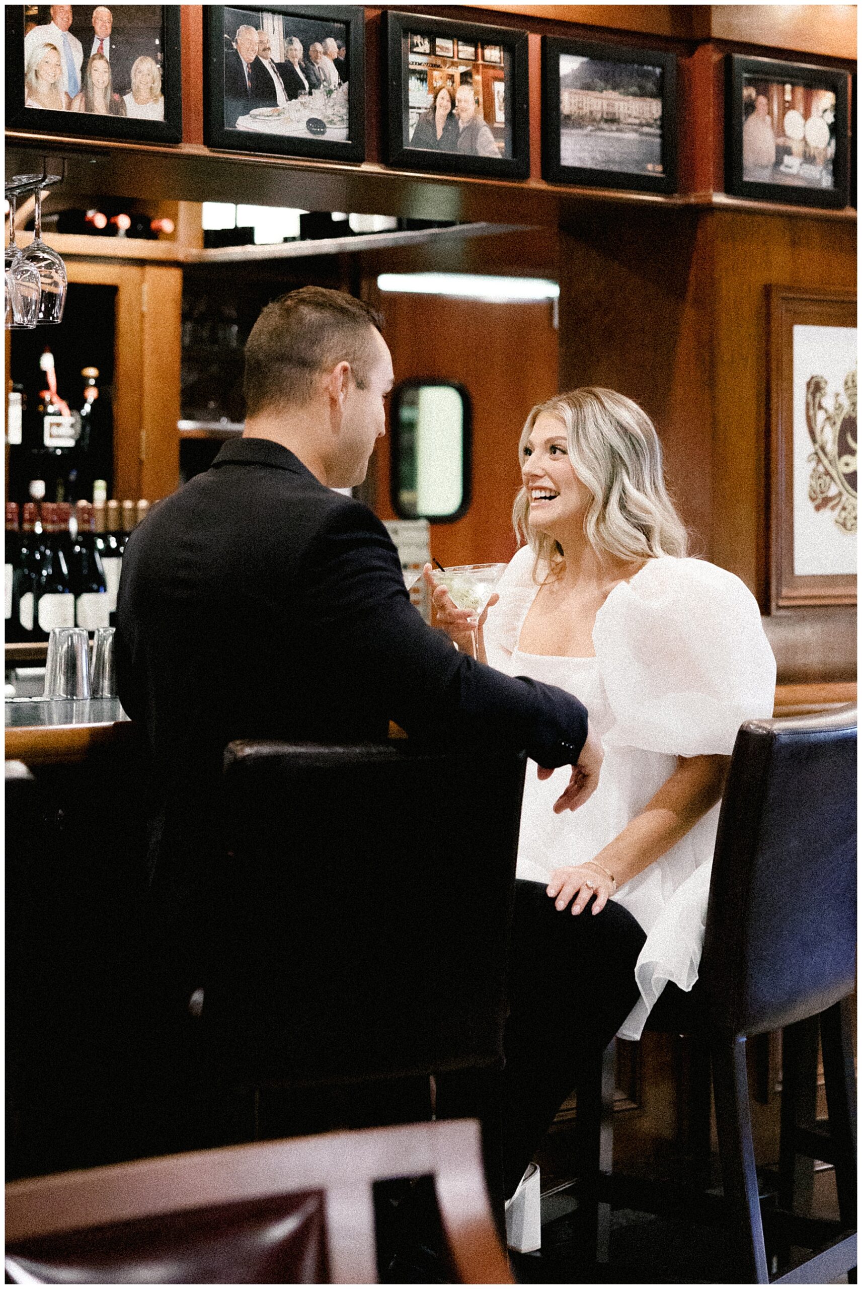 candid engagement photos of couple sitting at bar