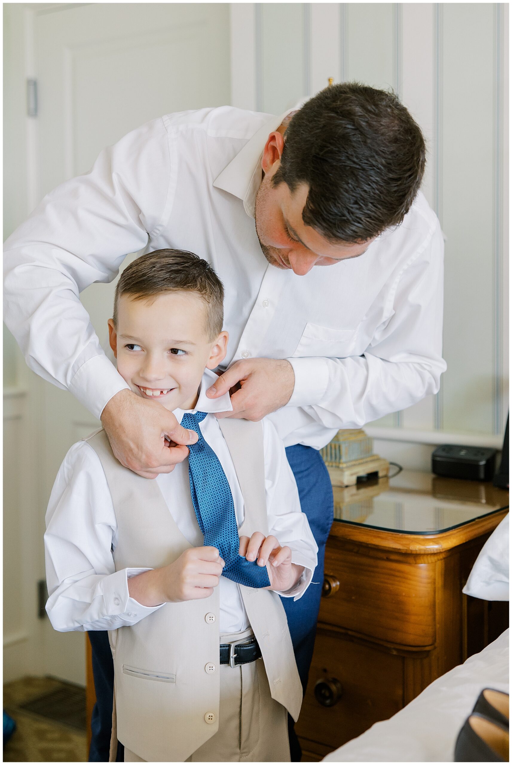groom helping stepson with tie on morning of wedding