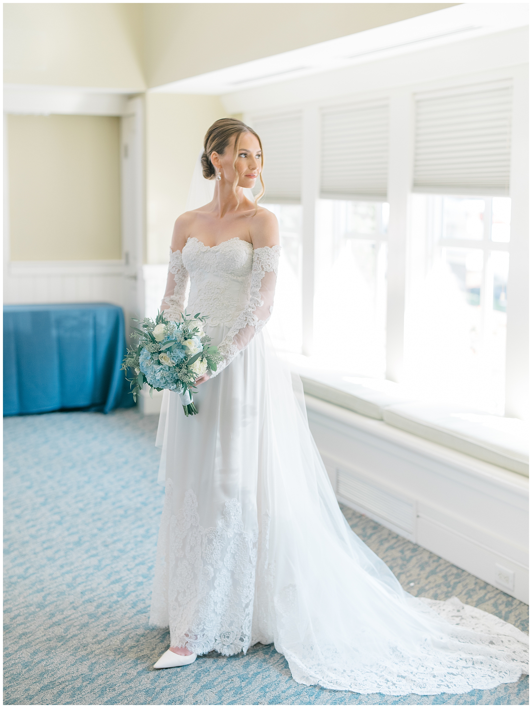 elegant bridal portraits of bride in gown holding bouquet and looking out window
