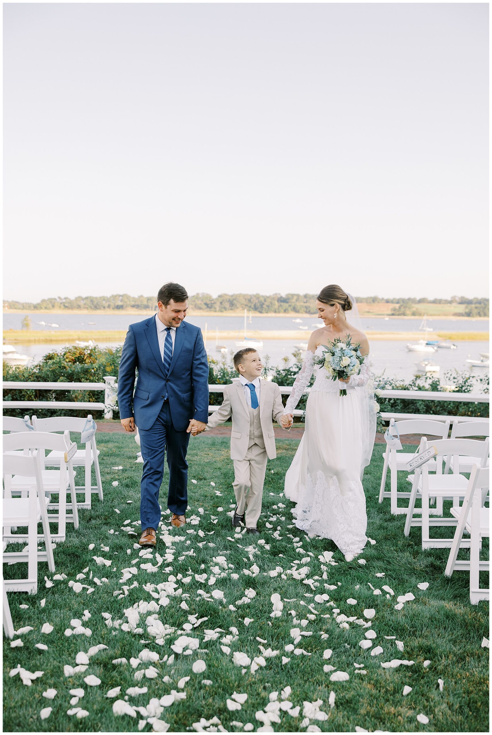 family of three hold hands as they walk down aisle together after wedding ceremony