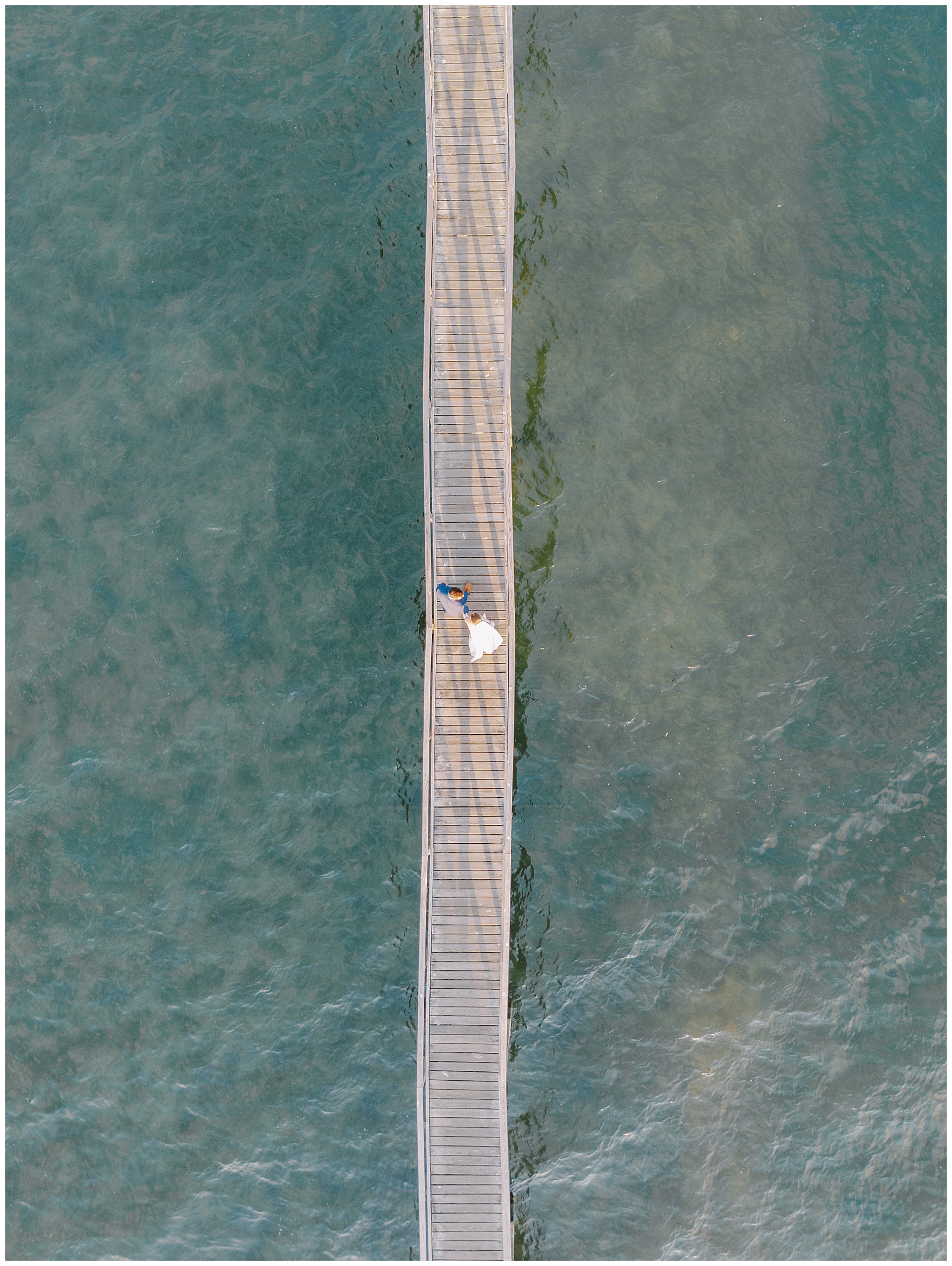 aerial photo of bride and groom on boardwalk over the ocean