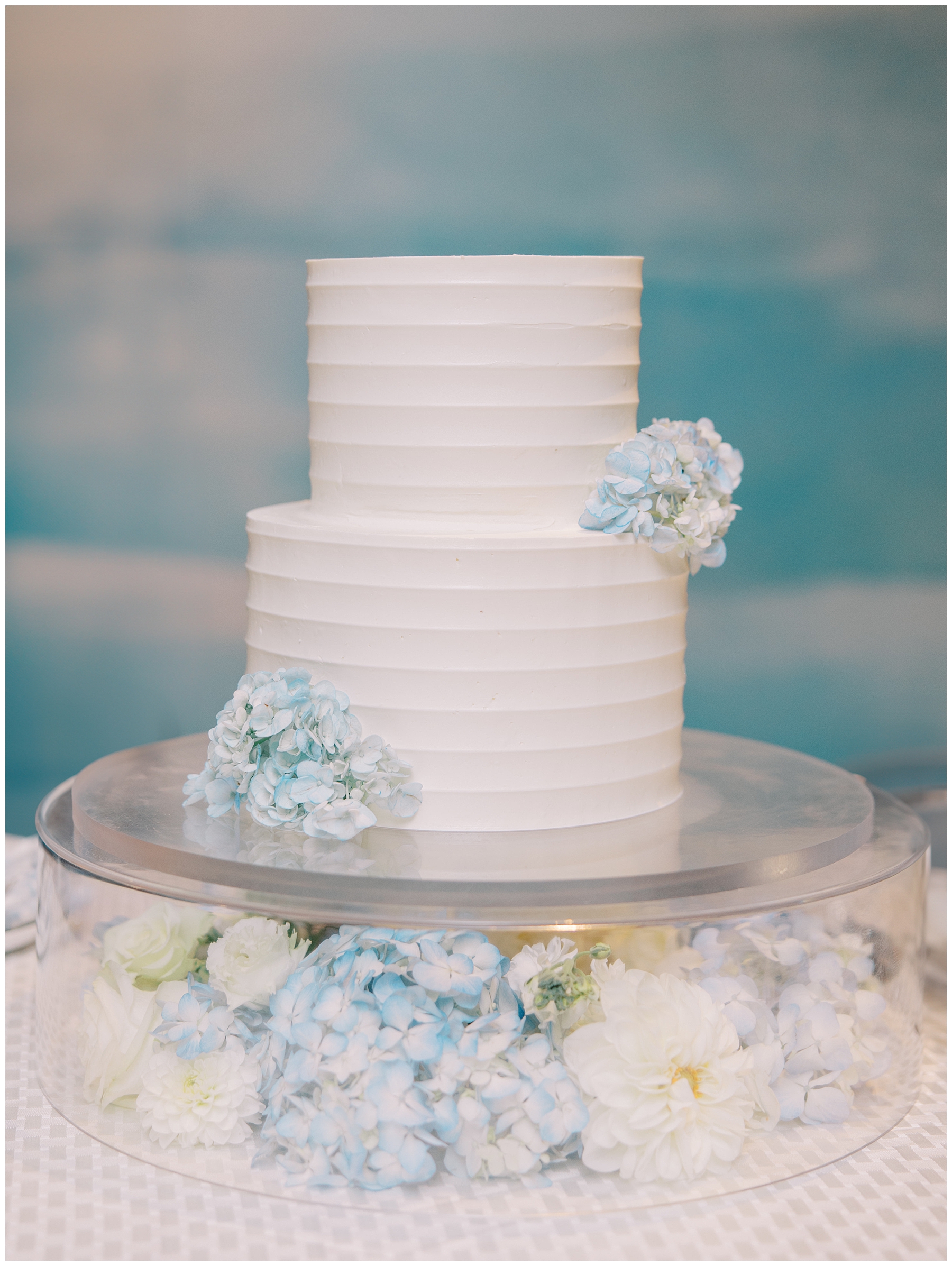 classic wedding cake surrounded by blue hydrangeas