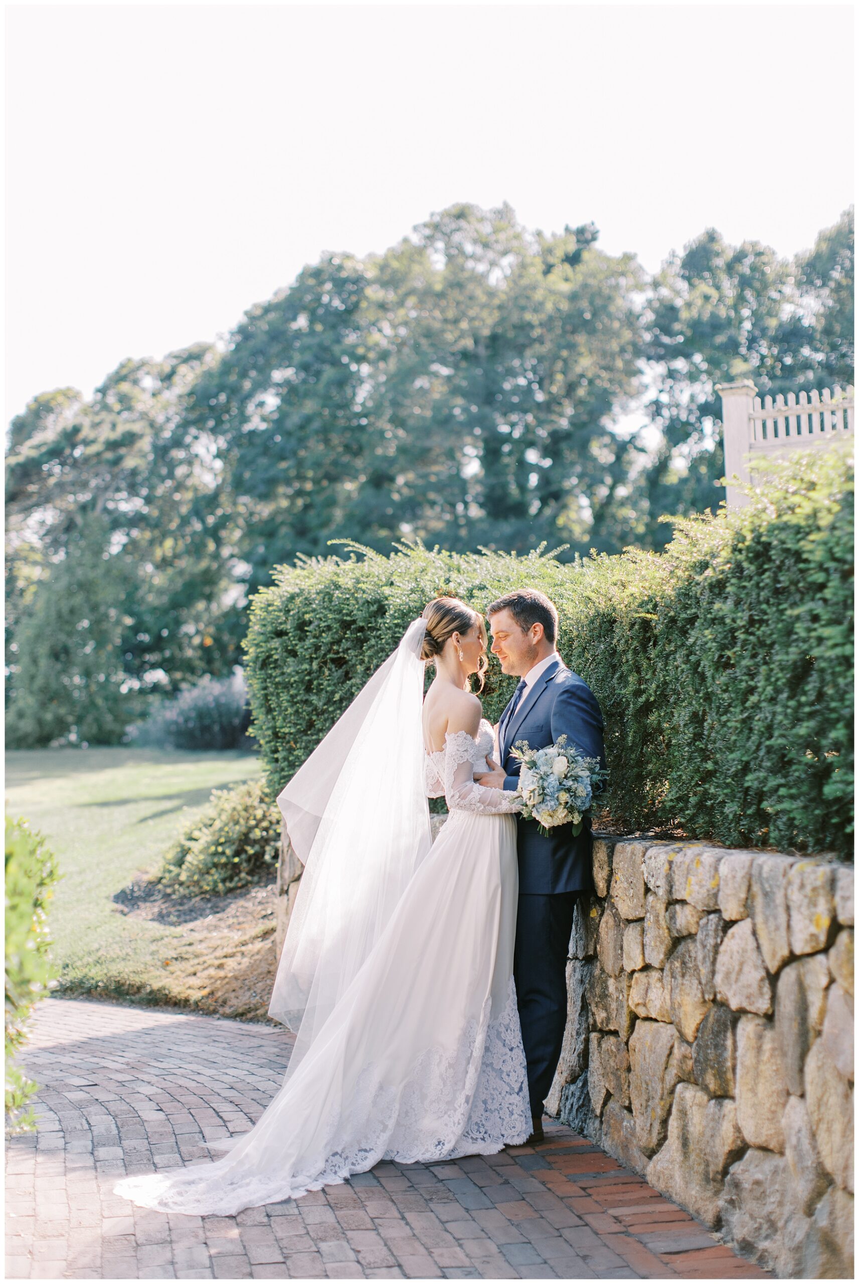 bride and groom lean against stone wall