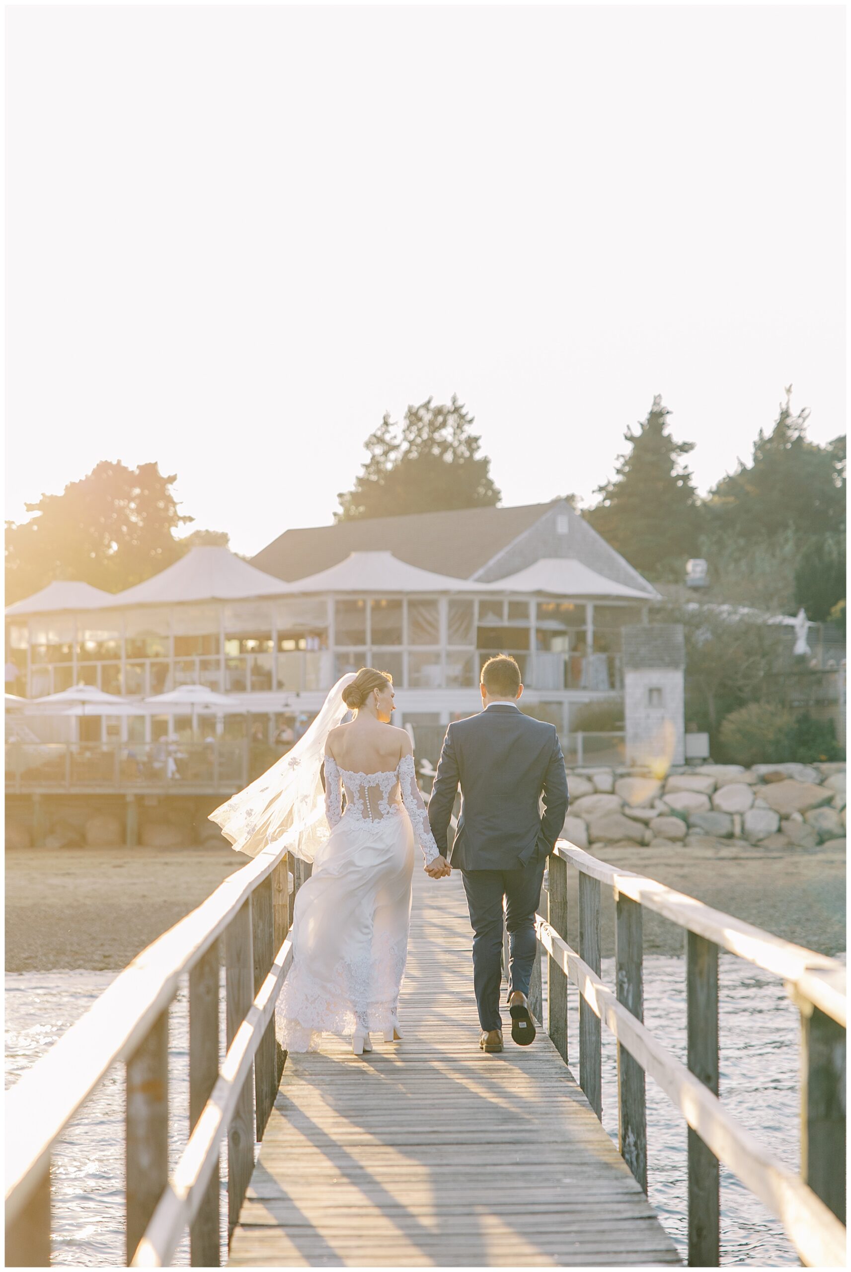 bride and groom walk on boardwalk back towards Wequassett Resort in Cape Cod