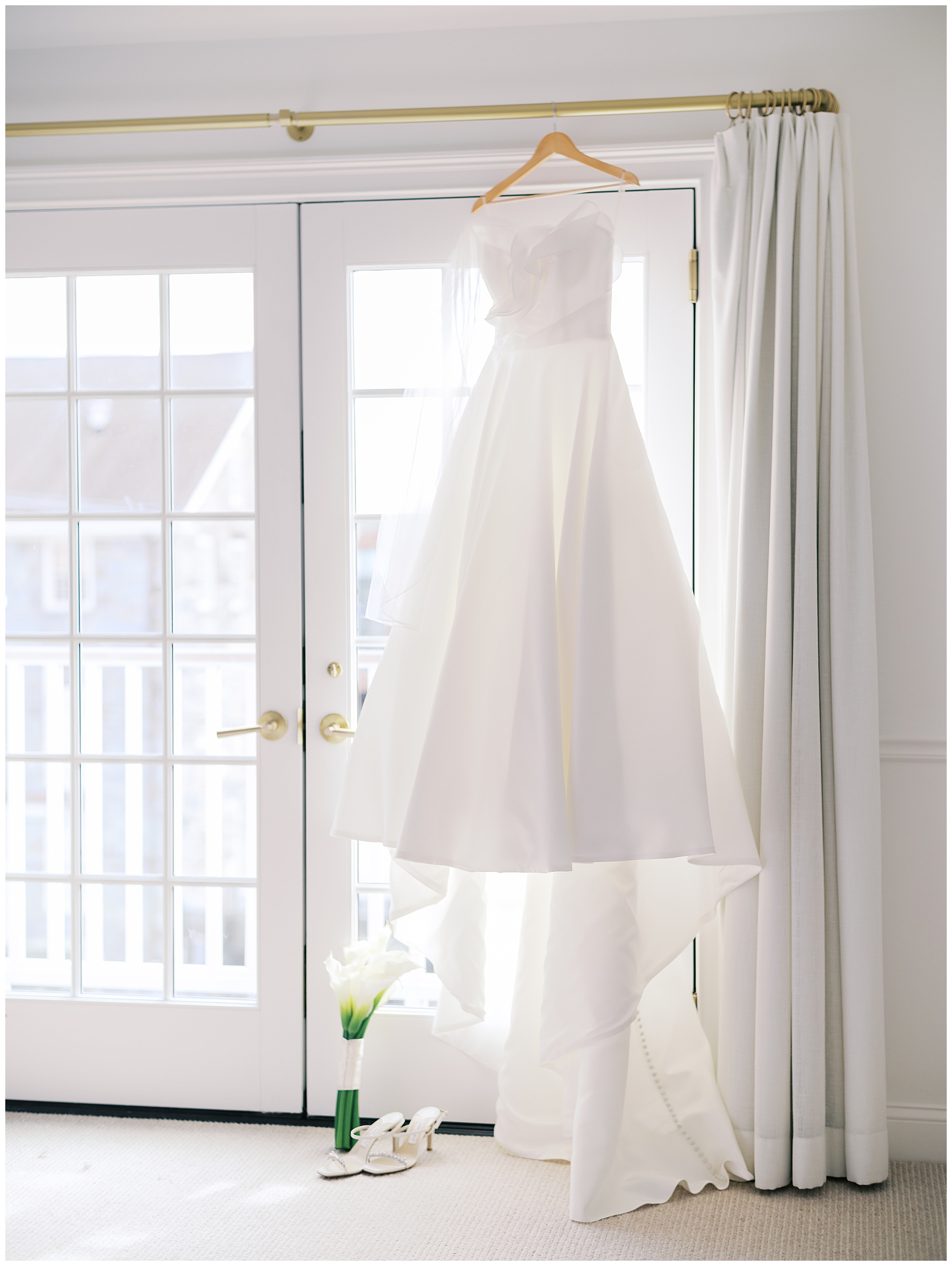 bride's wedding dress hanging by window