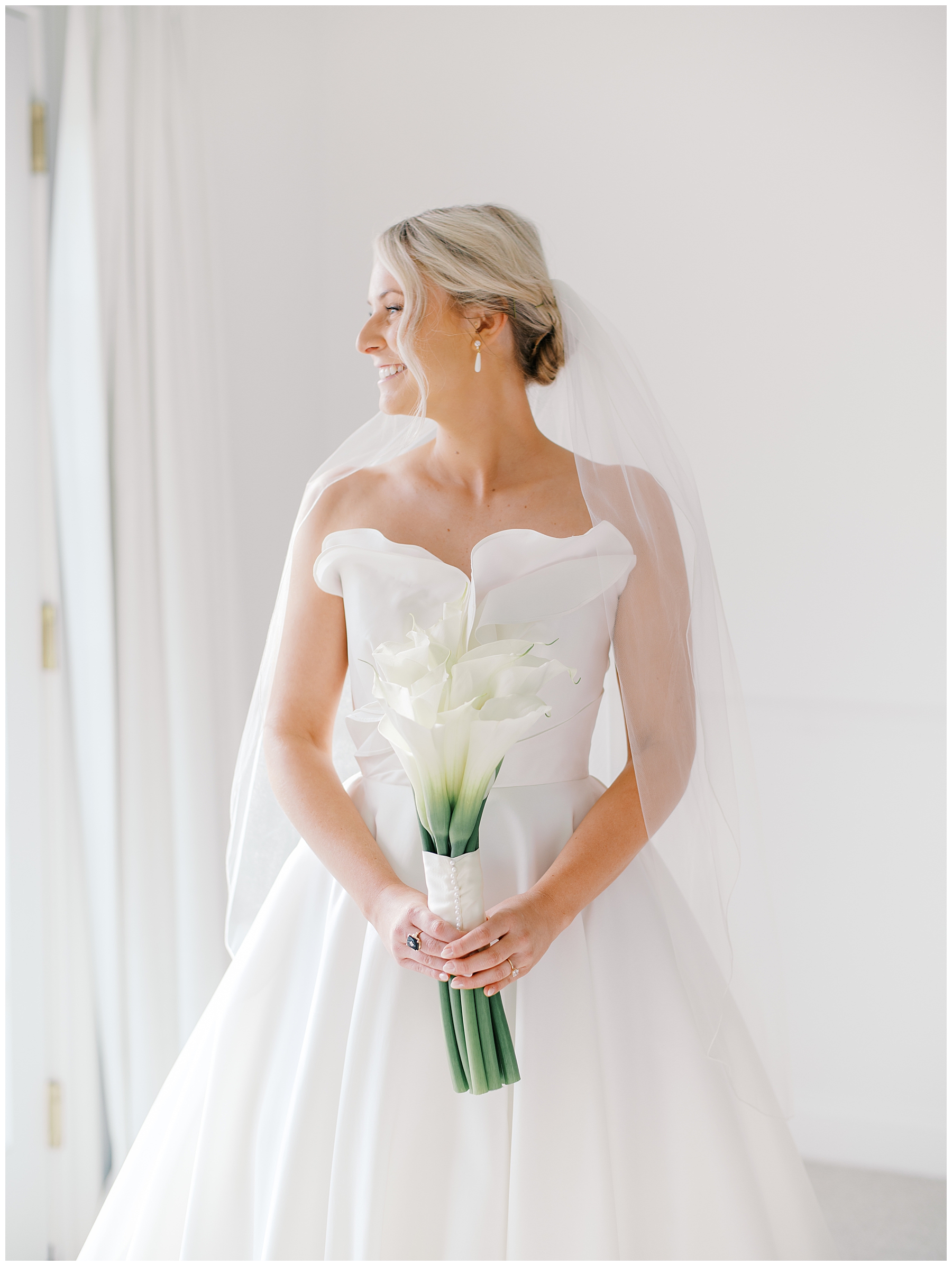 elegant bride in strapless wedding dress looks out window