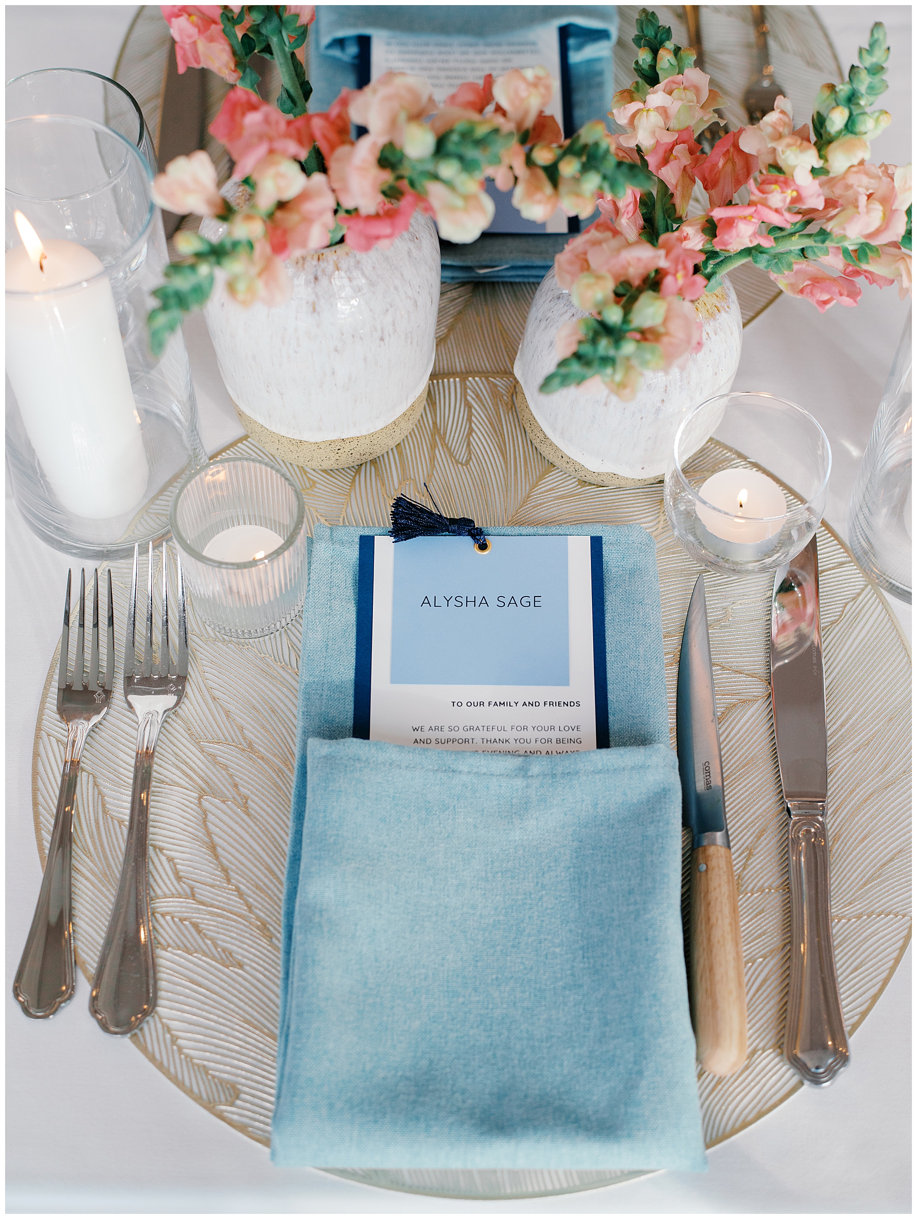 wedding place setting featuring menu tucked in light blue napkin and flickering candles