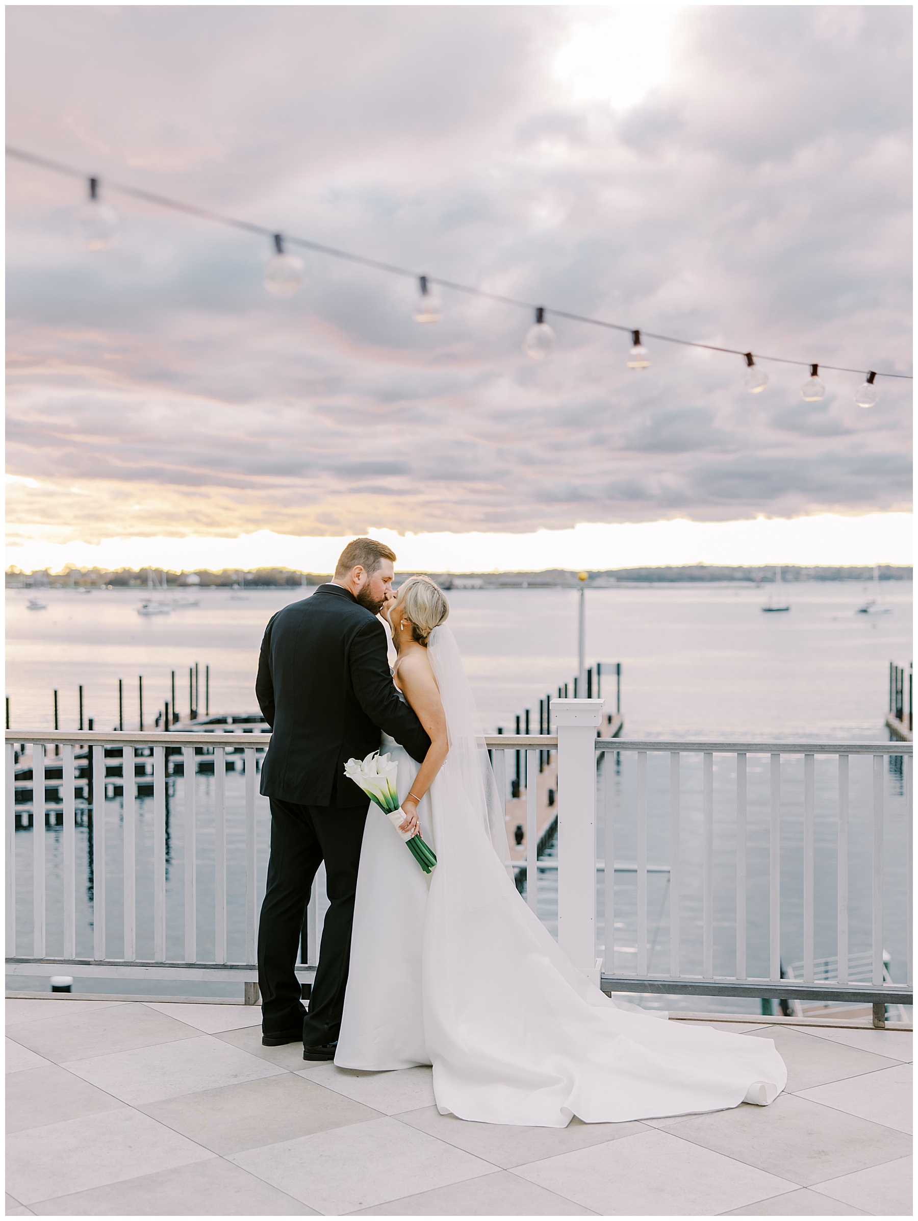 Couple kiss on outdoor patio of the Gardiner House overlooking the water in Newport, RI