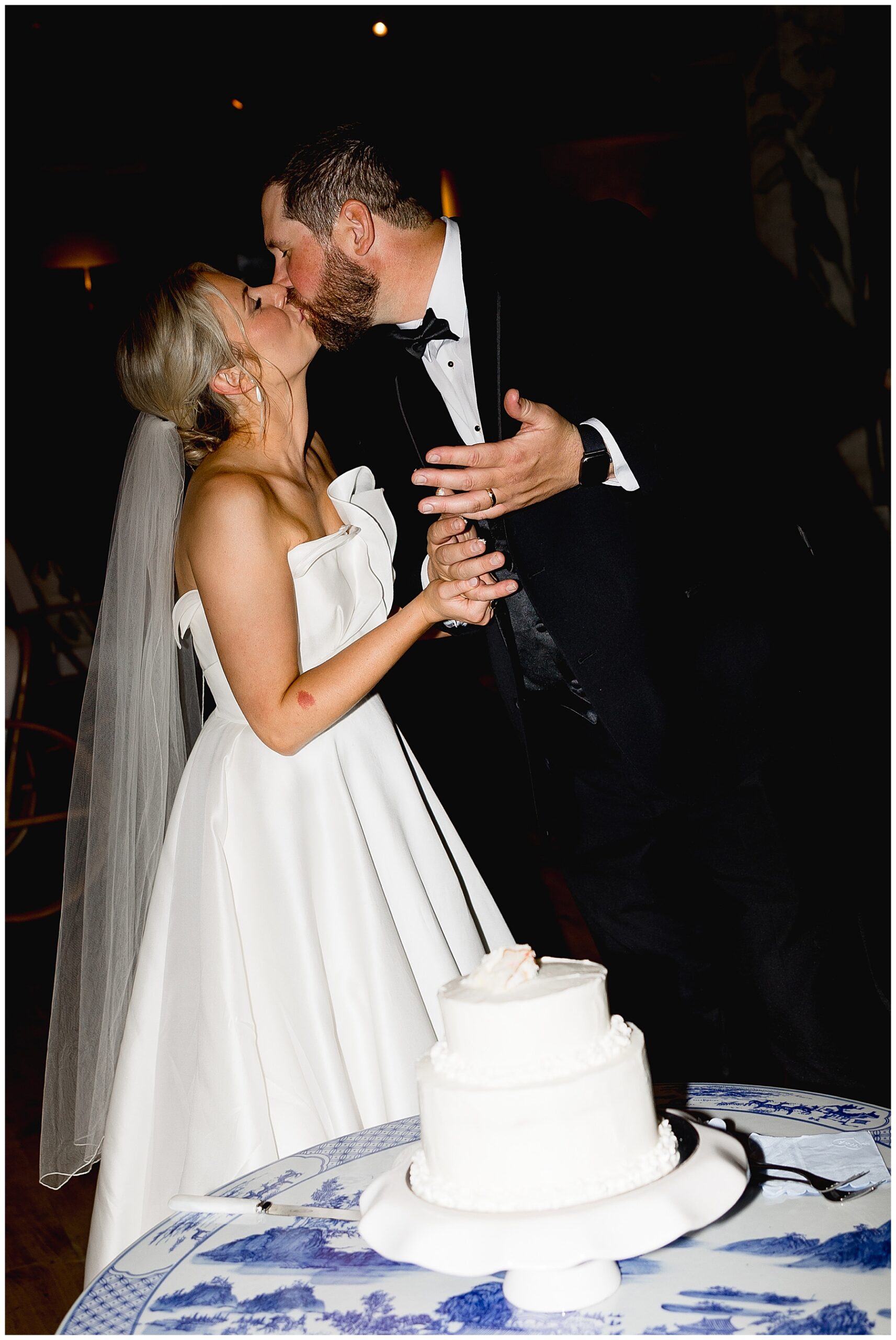 newlyweds kiss by their wedding cake