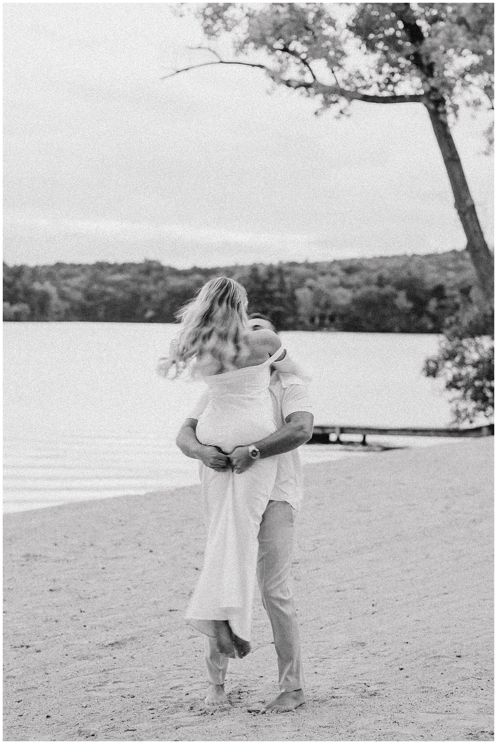 romantic Lake Pearl Wrentham engagment portrait as man lifts up his fiance
