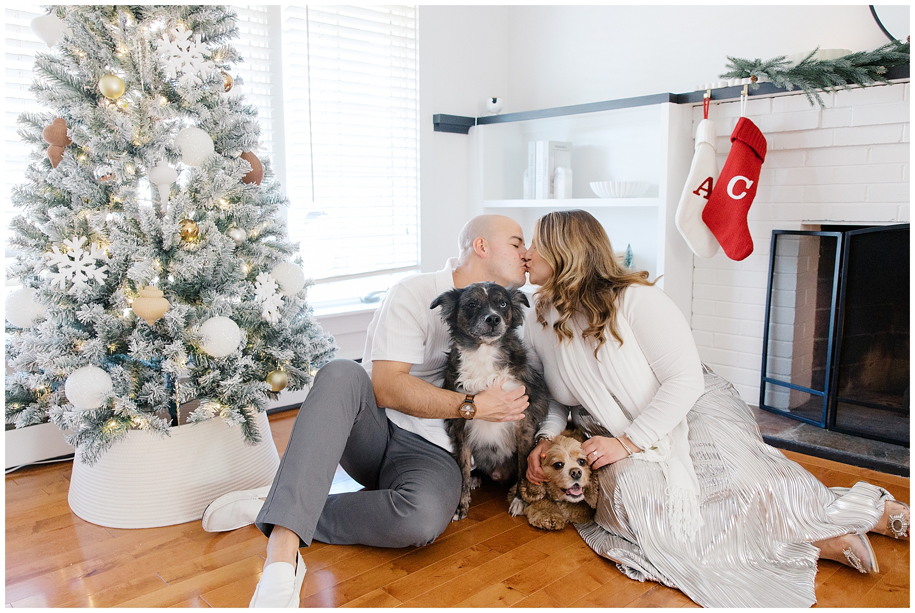 newly engaged couple kiss while holding their two dogs