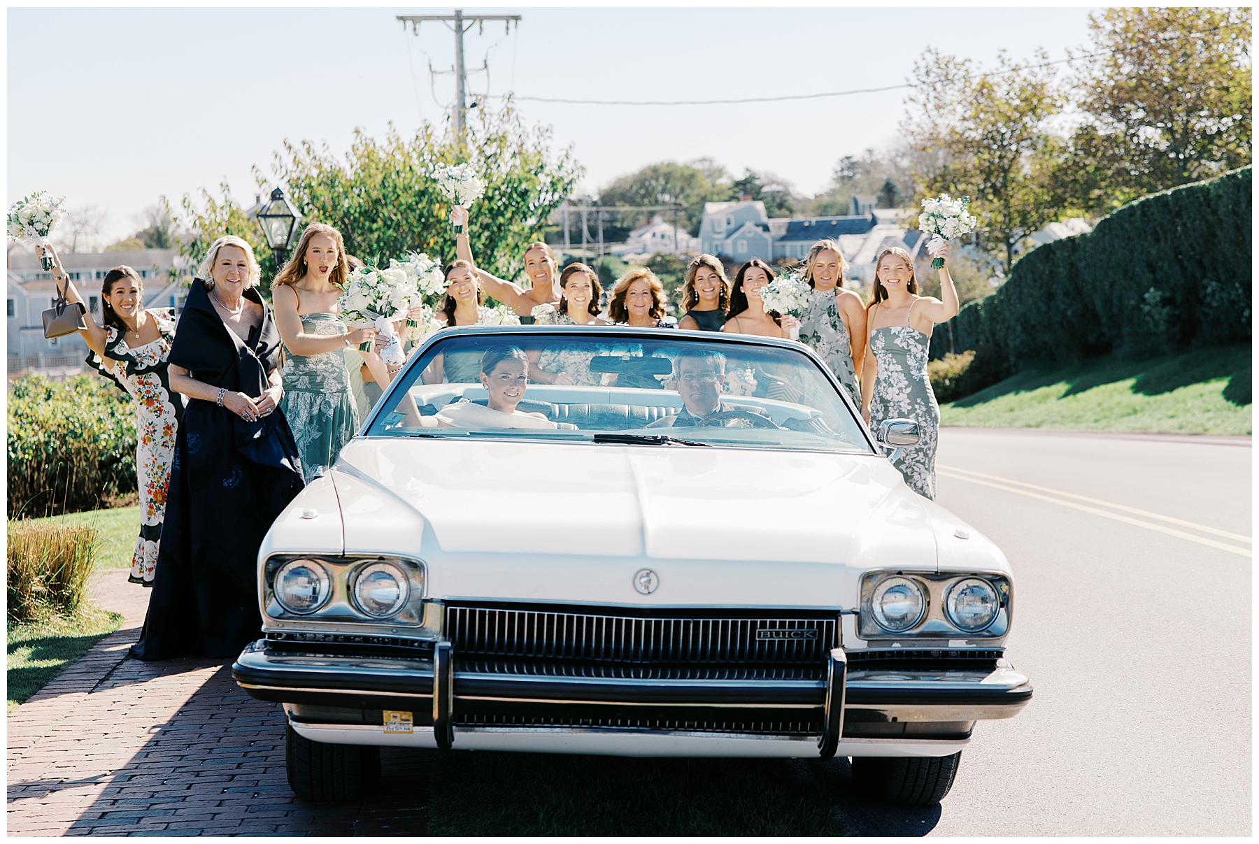 bride in car with father as bridesmaids stand behind car