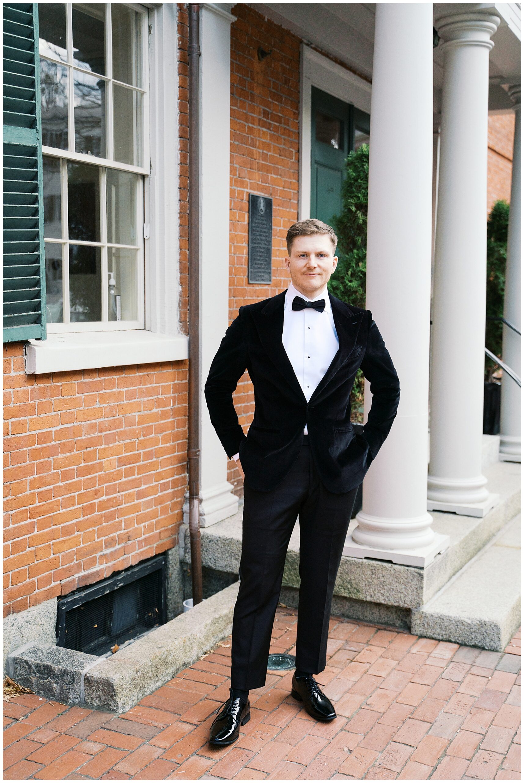 groom in tux stands outside of Hamilton Hall in Salem, MA