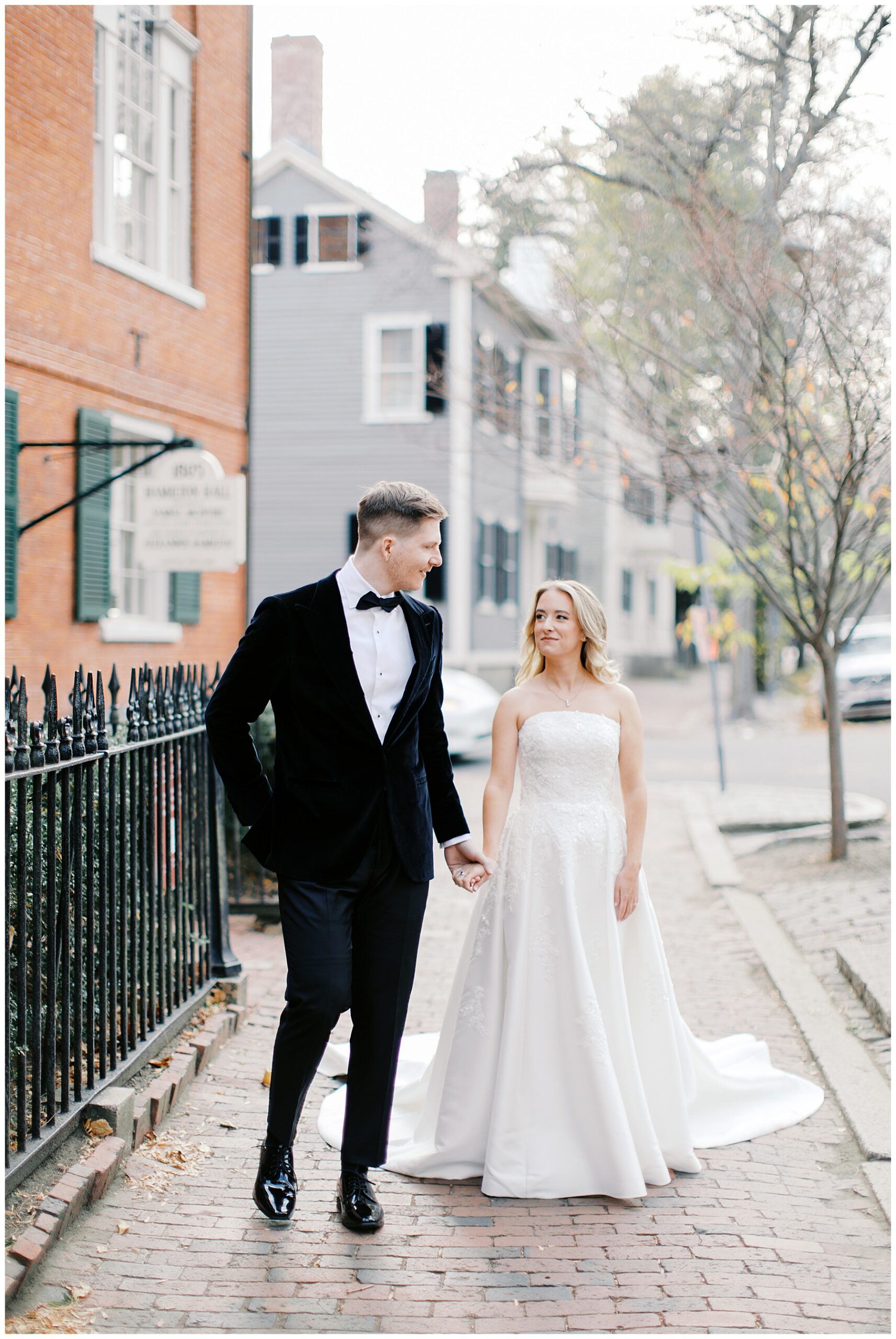 bride and groom walk outside Hamilton Hall holding hands