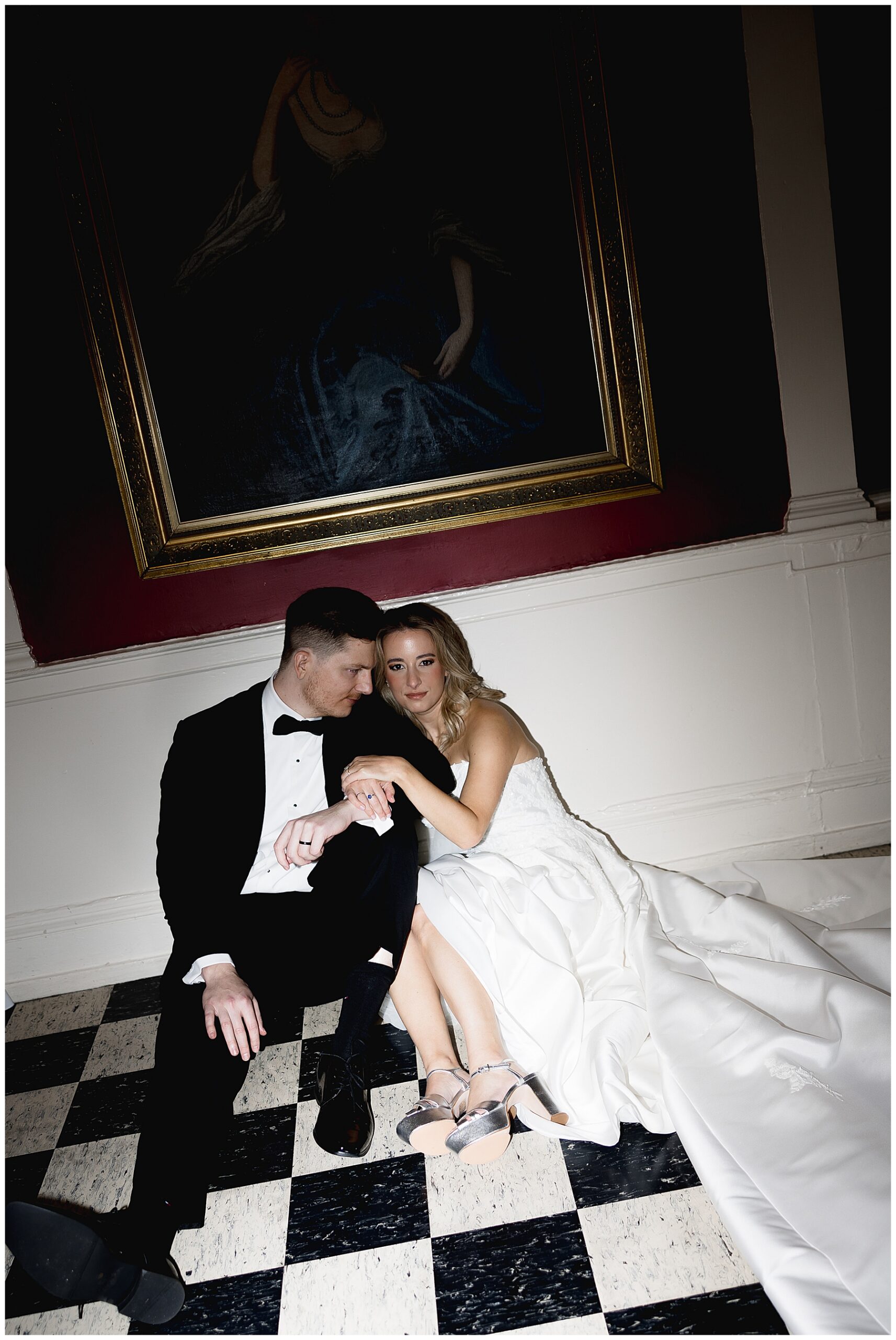 newlyweds sit under painting