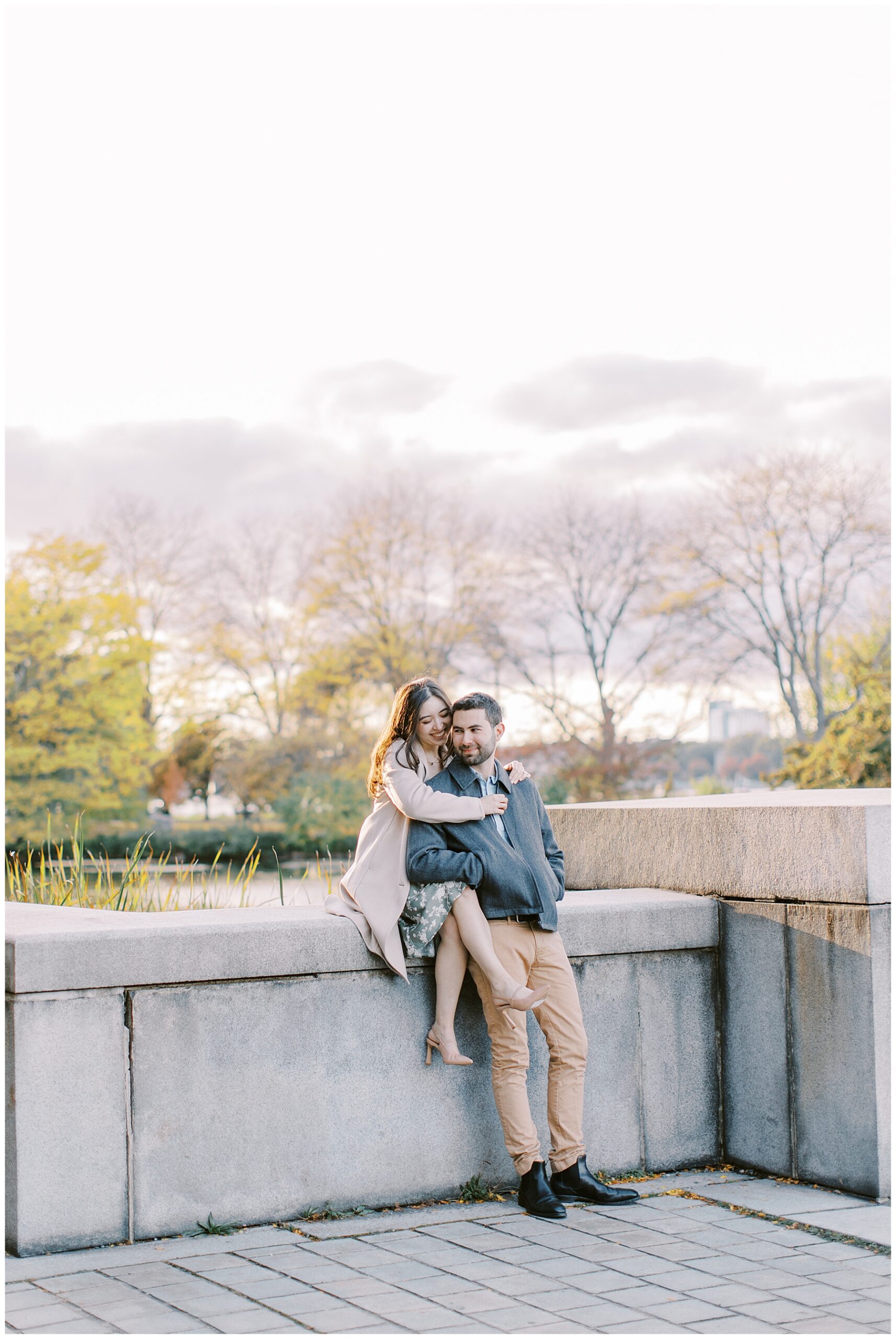 couple sit together on ledge during engagement session 