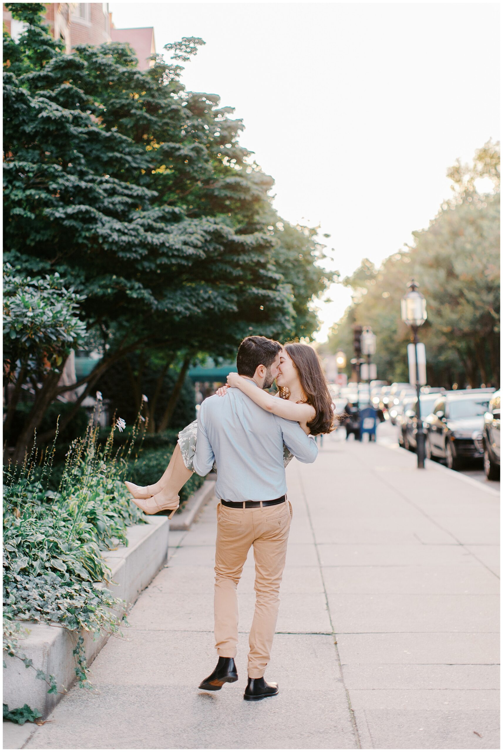 man carries his fiancé in his arms down sidewalk in Boston 