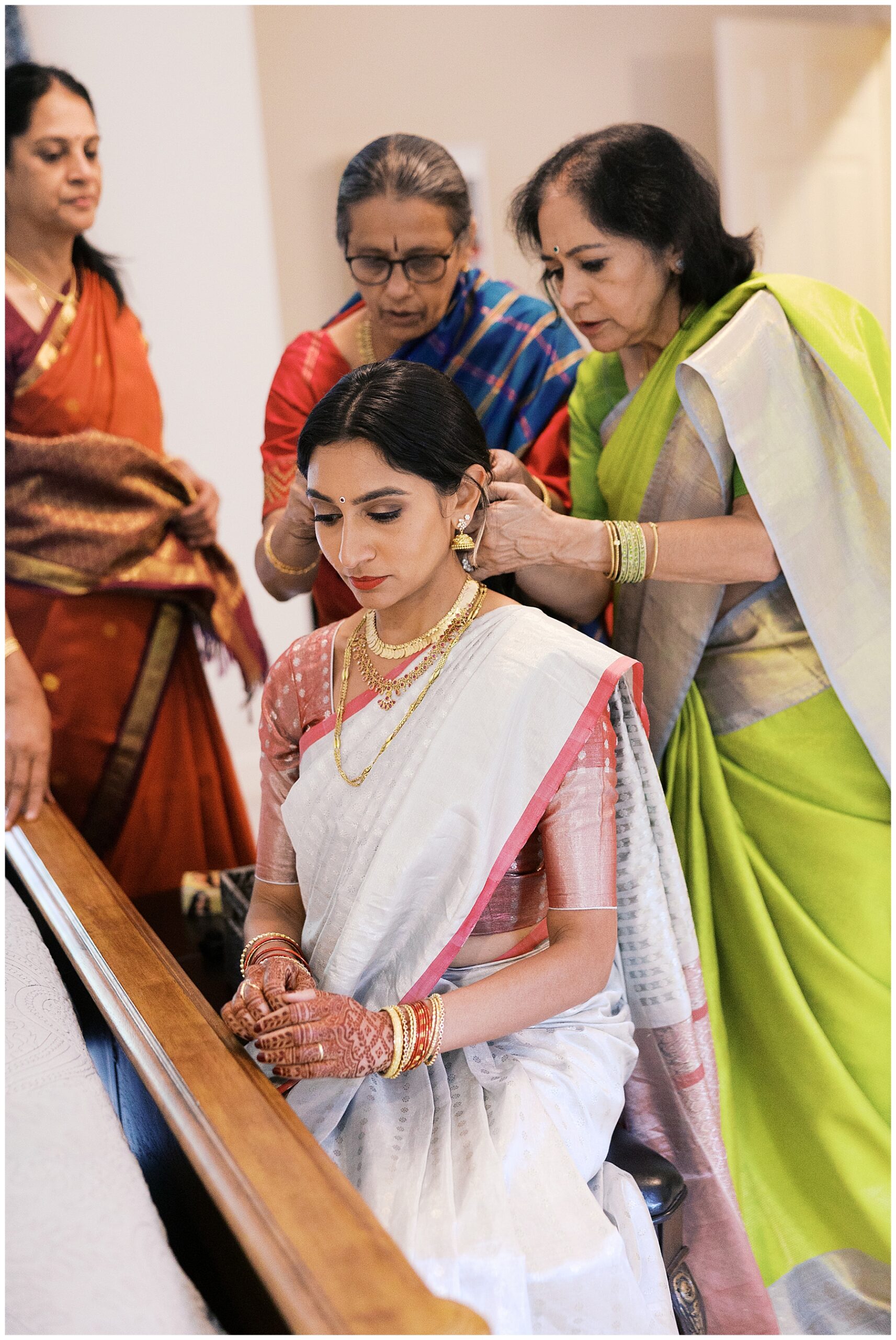 family helps bride put wedding jewelry on