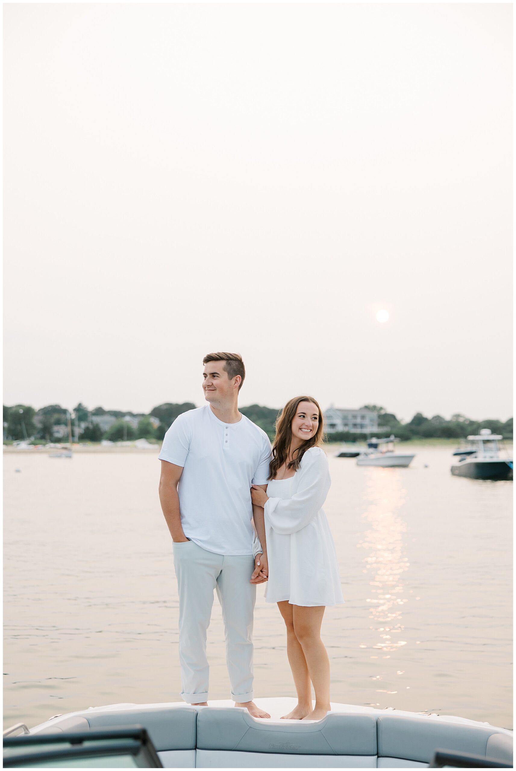 couple stand on back of boat on the water
