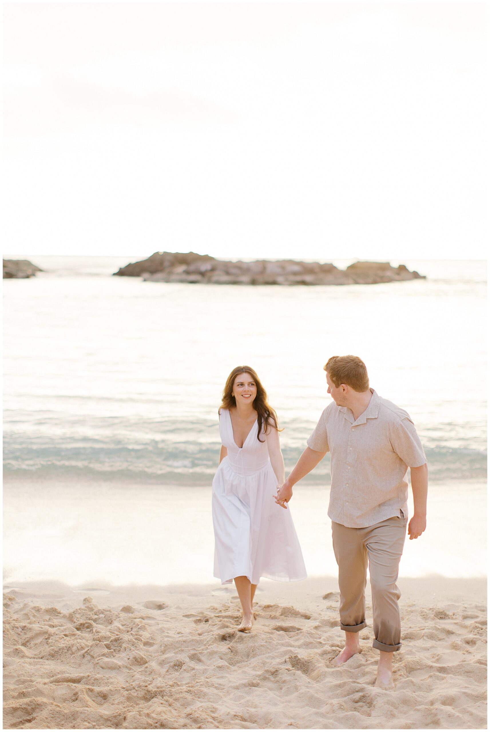 couple walking the beach at sunset in O'ahu, Hawaii