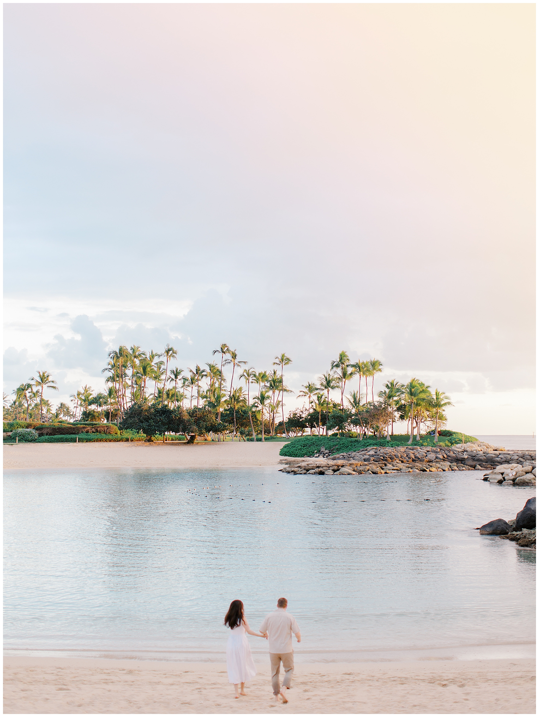 destination photographed captures engaged couple walking towards ocean in Hawaii