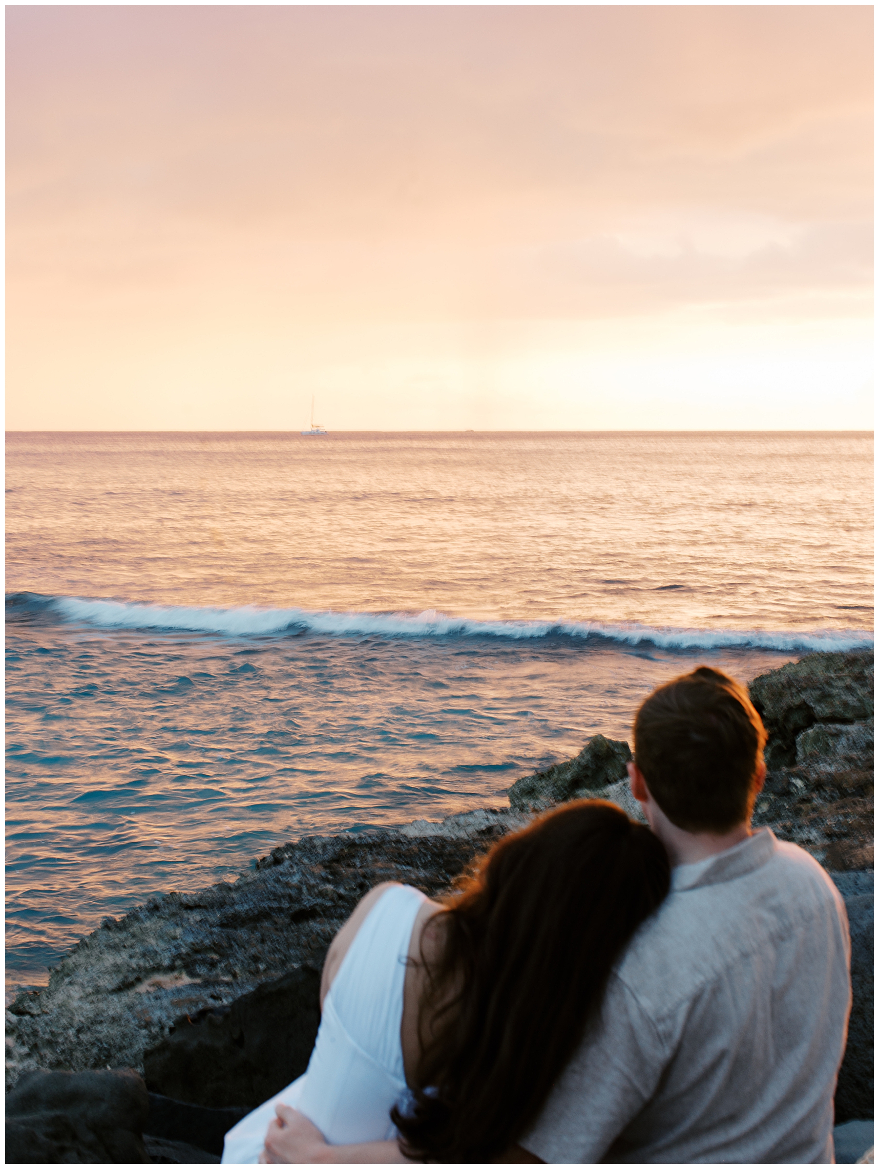 engaged couple watch the sun set over the ocean during O'ahu Hawaii Engagement Session