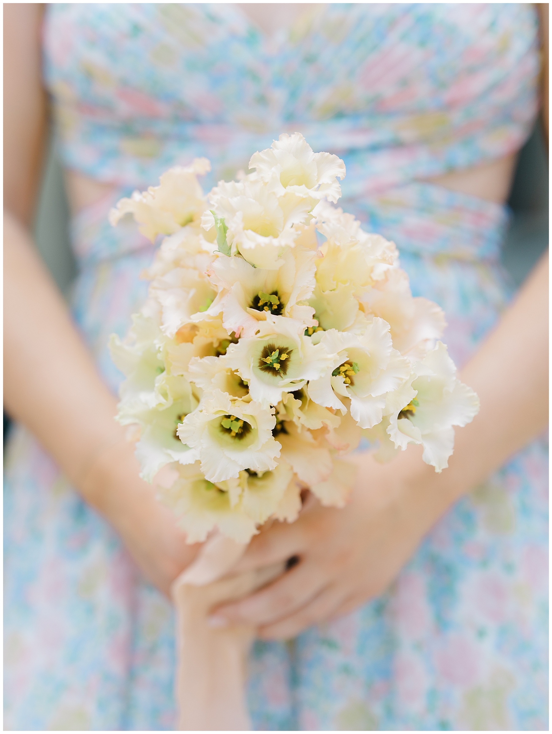 bridesmaid carries light yellow floral bouquet that coordinates with floral dress
