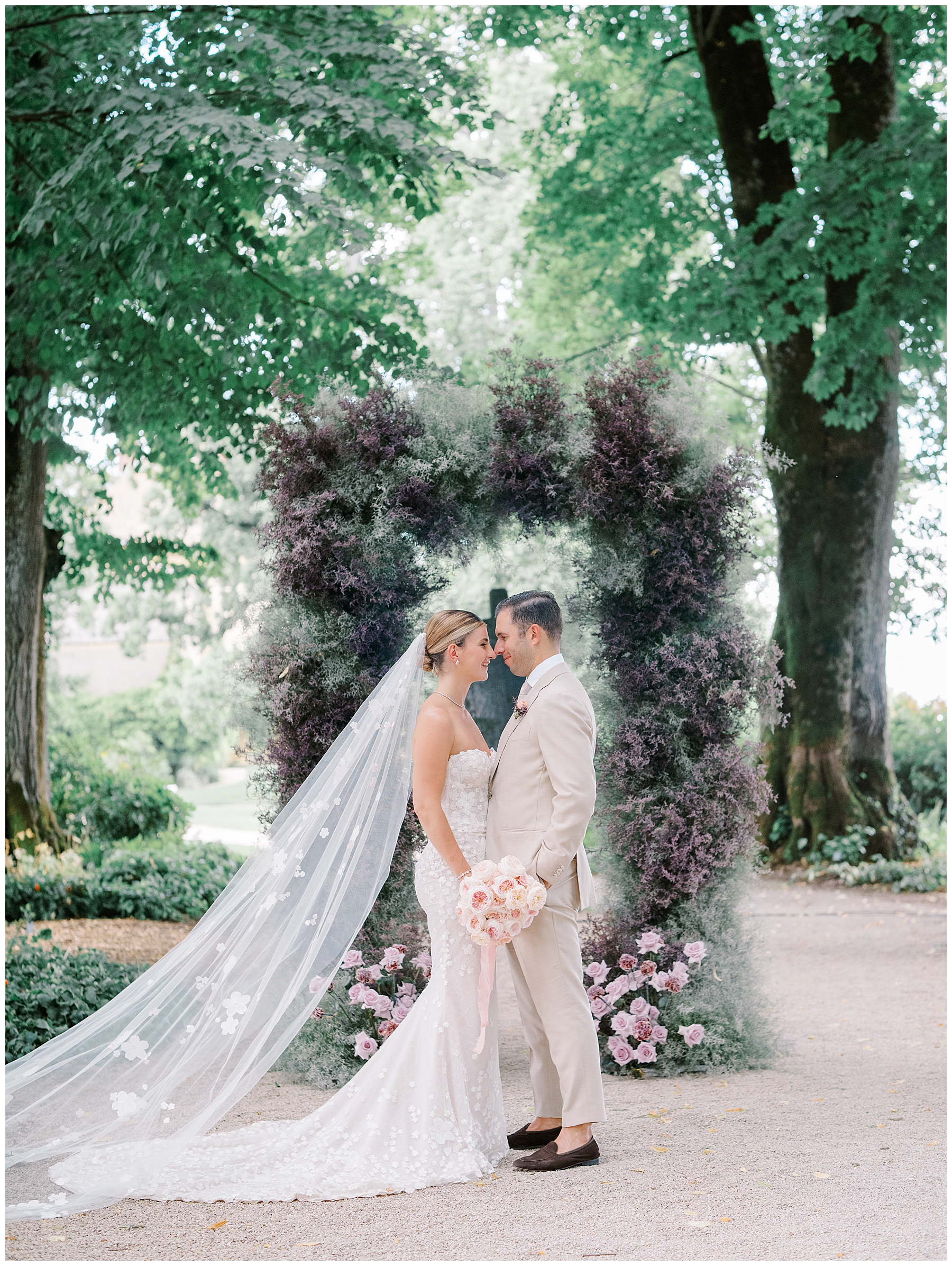 newlywed photos in front of whimsical wedding arch