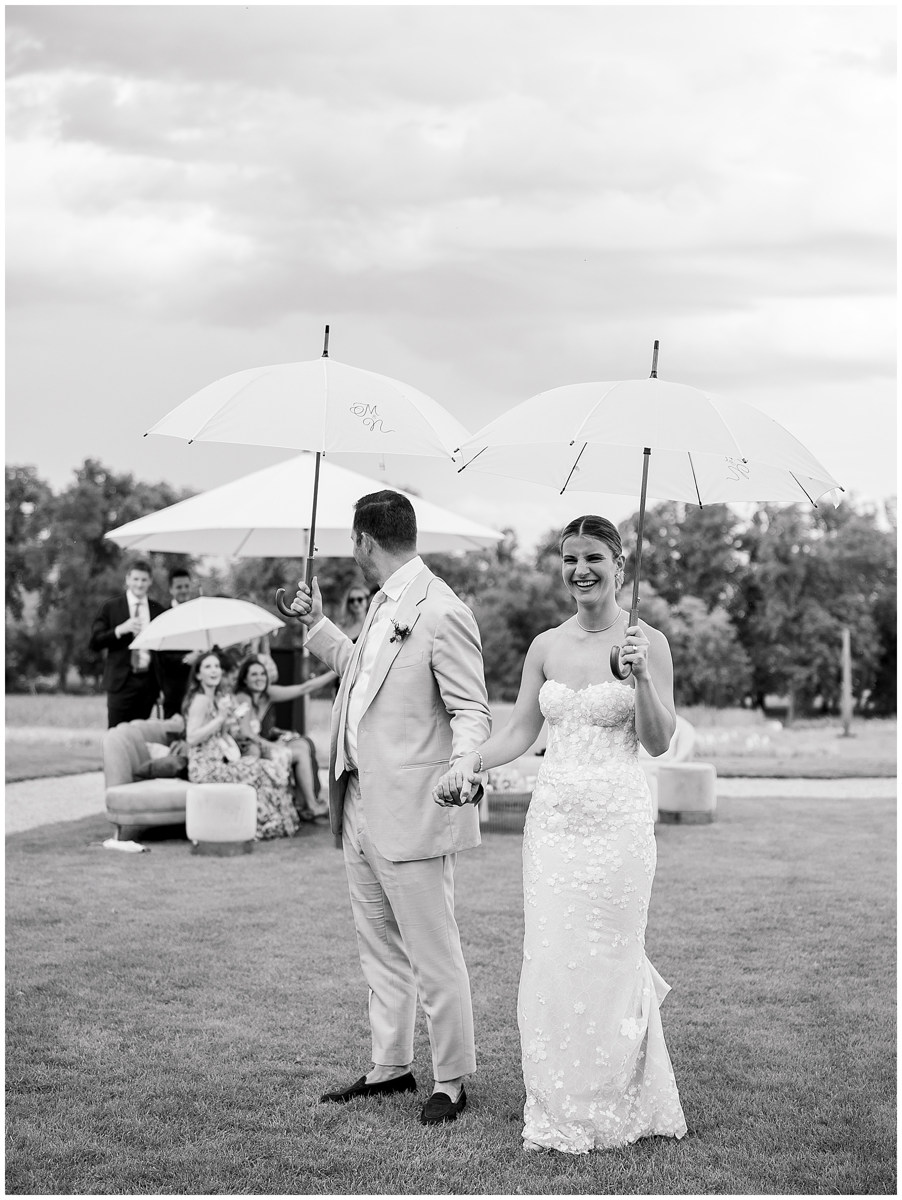 bride and groom hold umbrellas during rain shower at cocktail hour