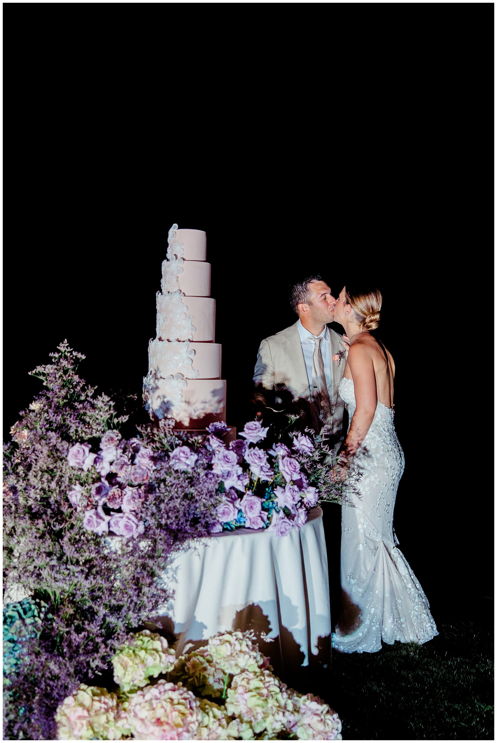 bride and groom kiss by wedding cake