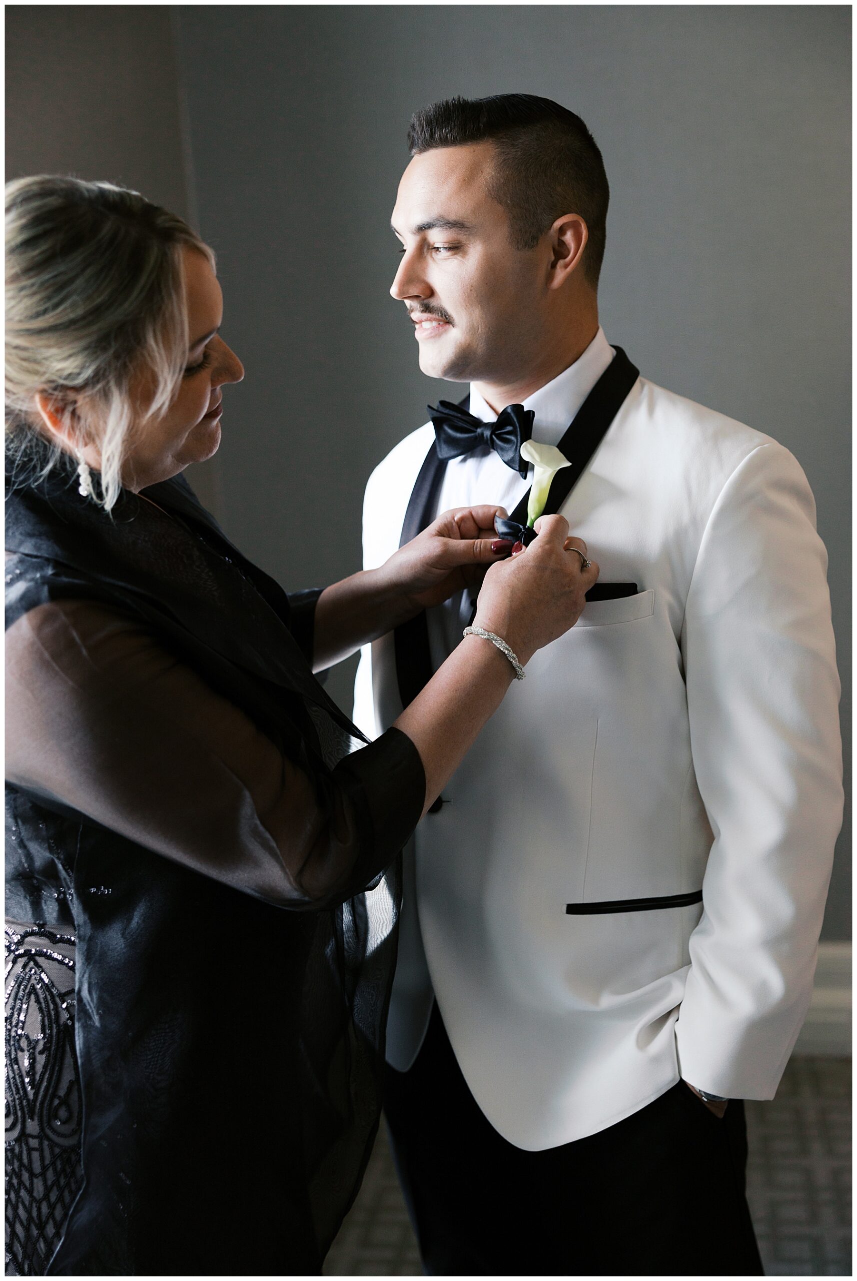 mother of groom helping him with boutonniere 