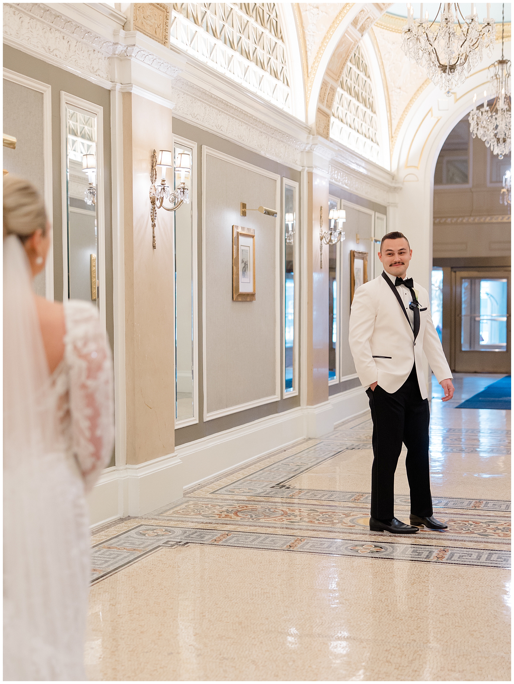 groom in white tux in luxurious hallway of Fairmont Copley Plaza for first look 