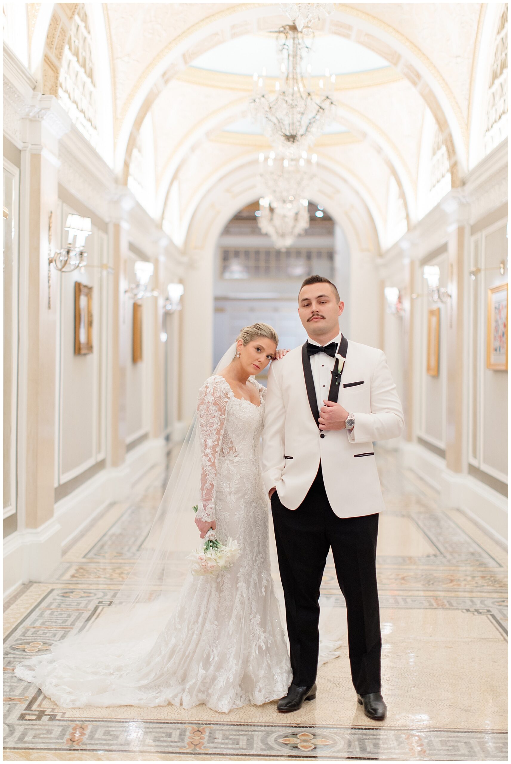 bride in dress and groom in white tux stand in hallway of Fairmont Copley Plaza in Boston