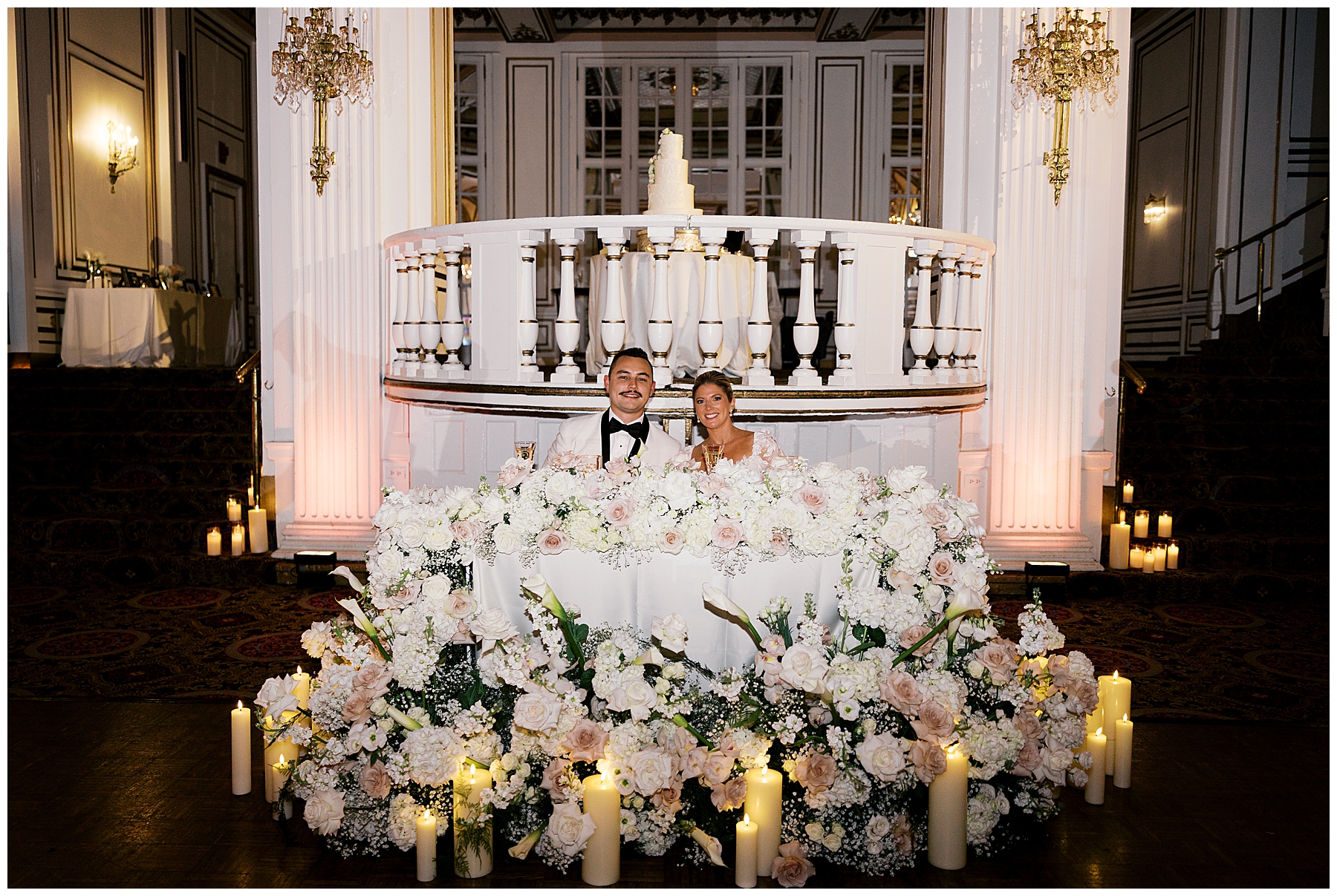 bride and groom at sweetheart table surrounded by florals