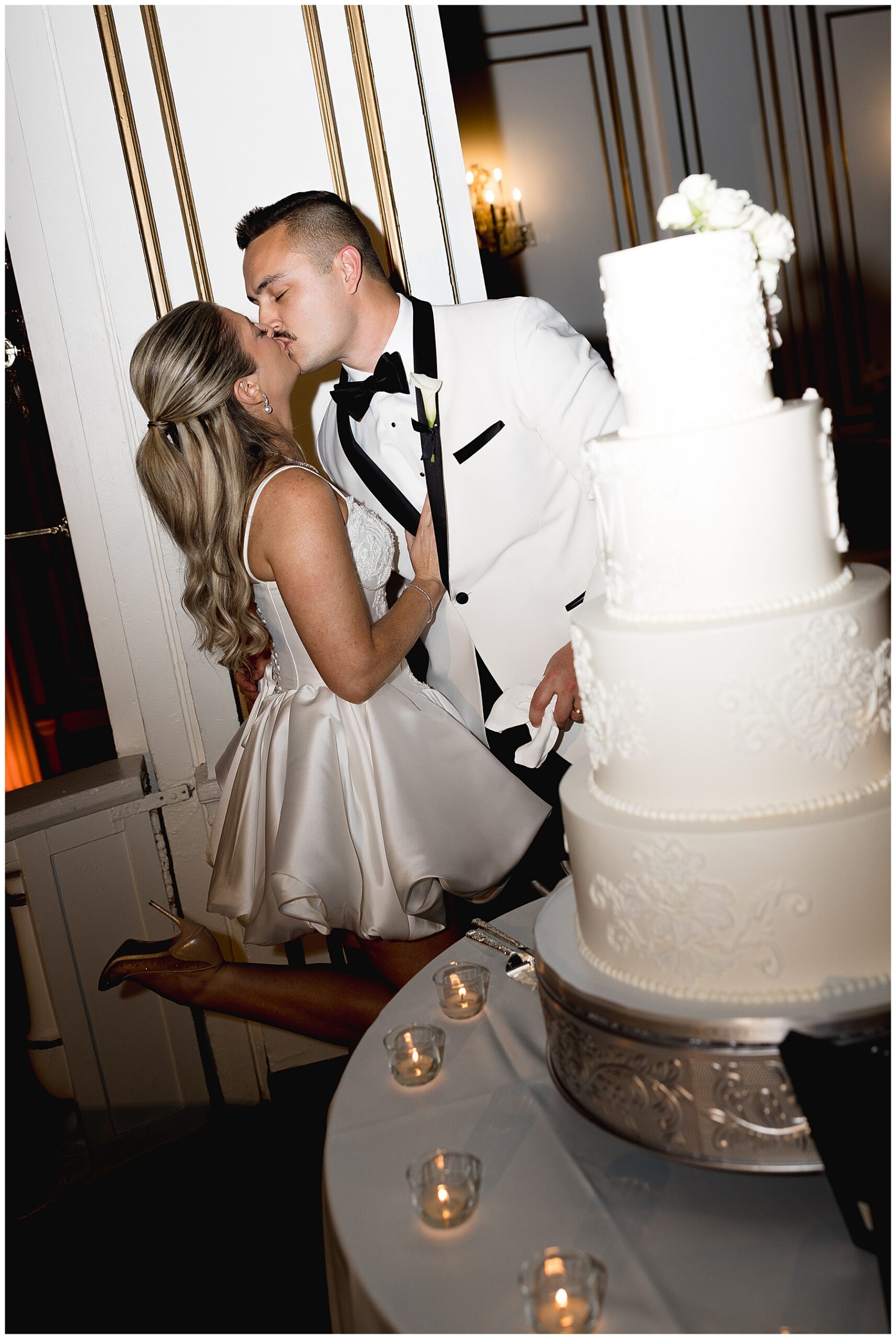 bride and groom kiss by wedding cake 