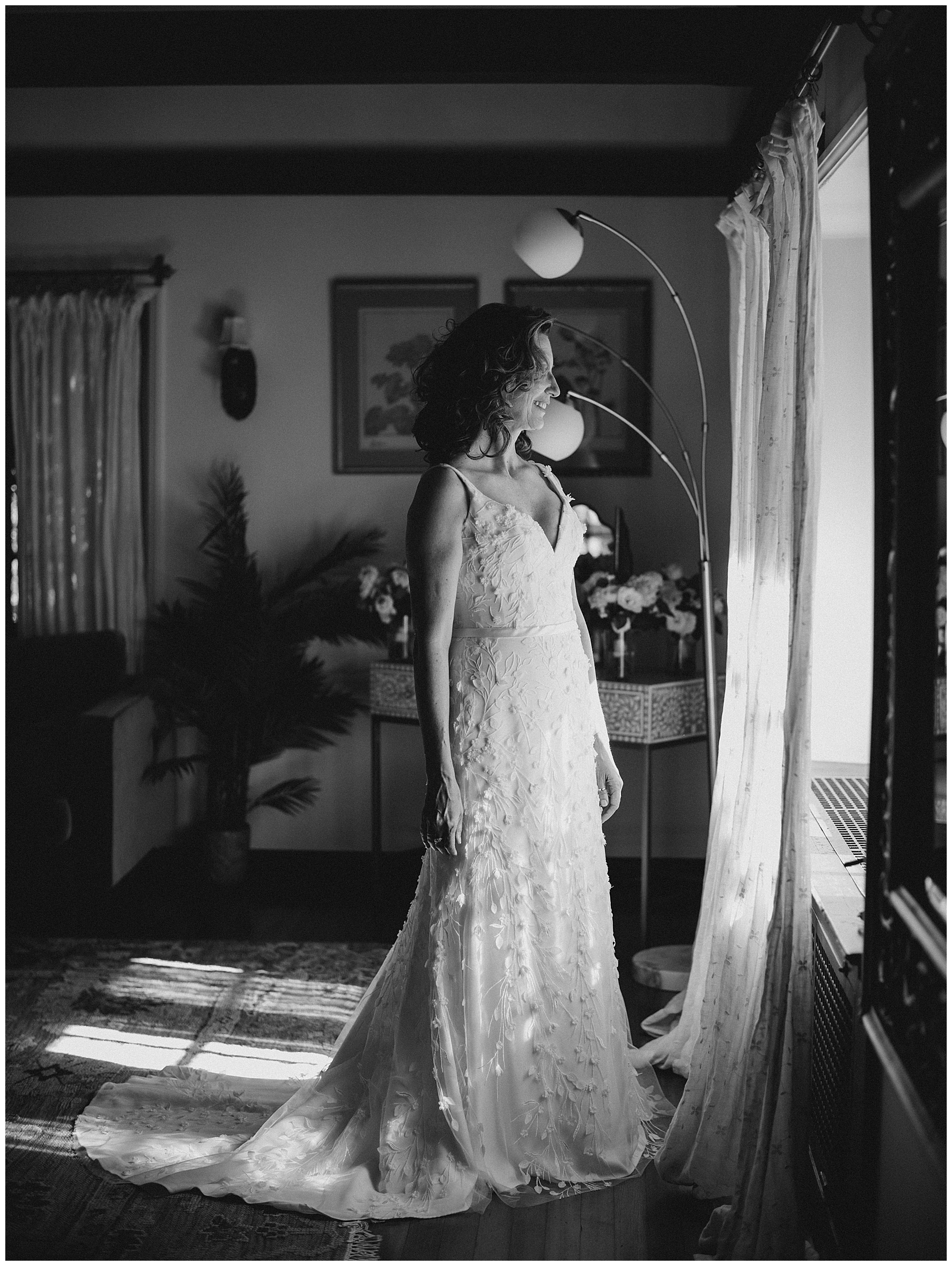 timeless photo of bride in wedding gown looking out window