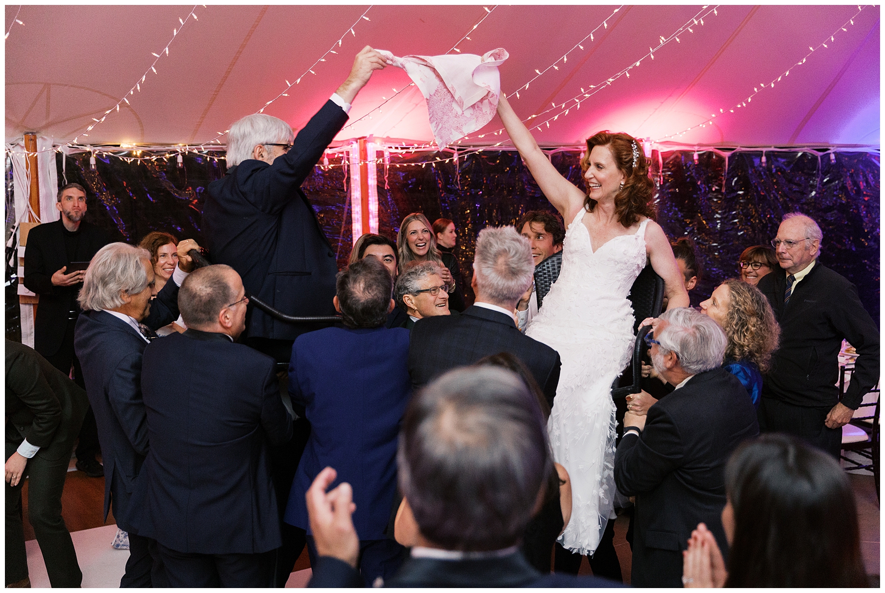bride and groom lifted up in chairs at wedding reception