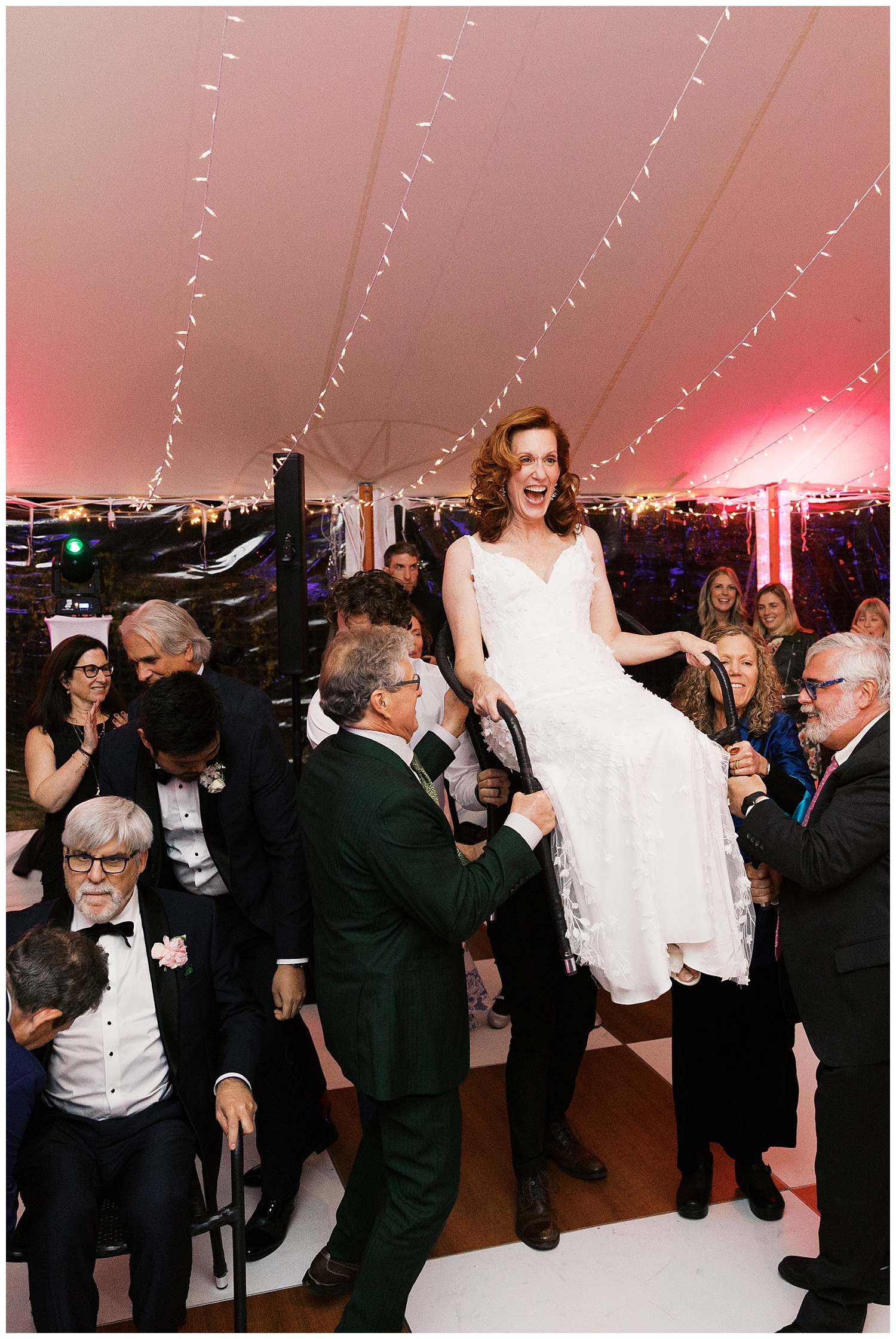 wedding guests lift bride and groom up on chairs
