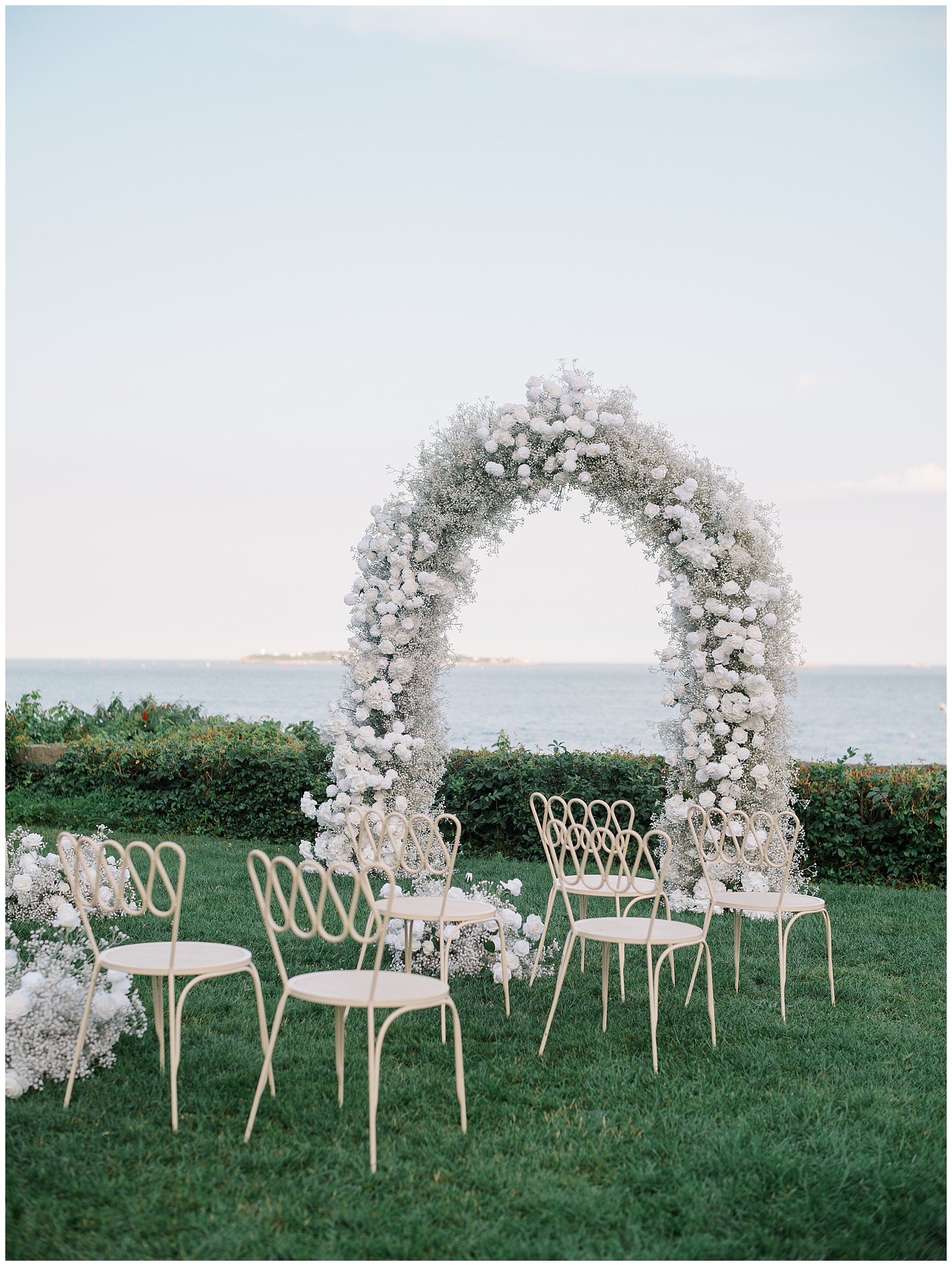 white floral wedding arch at wedding ceremony site facing the ocean